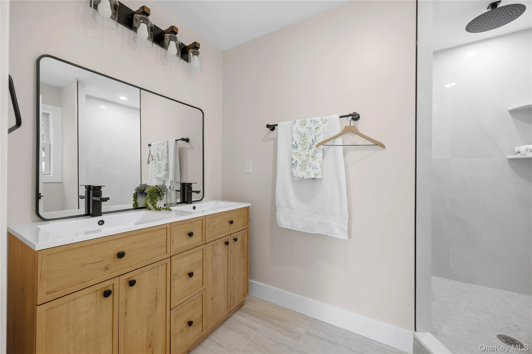 Dual vanity with a white countertop and integrated sinks, natural wood-finish cabinetry, and matte black fixtures Dual vanity with a white countertop and integrated sinks, natural wood-finish cabinetry, and matte black fixtures
