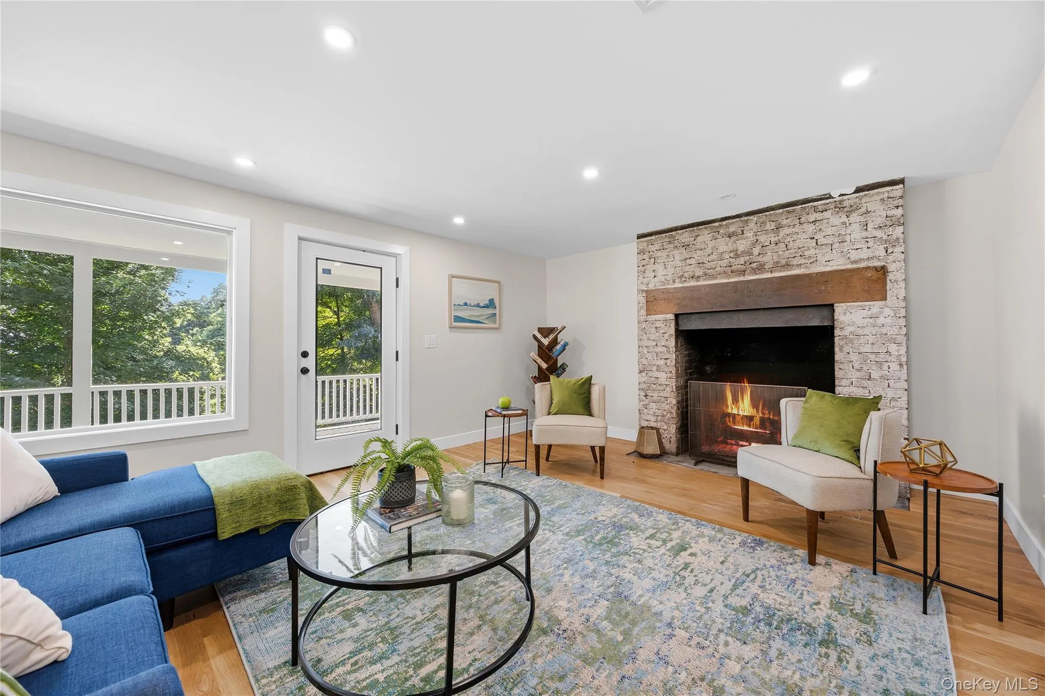 Hardwood flooring, recessed lighting, brick-faced fireplace with wood mantel, a large picture window, and direct access to an outdoor balcony Hardwood flooring, recessed lighting, brick-faced fireplace with wood mantel, a large picture window, and direct access to an outdoor balcony