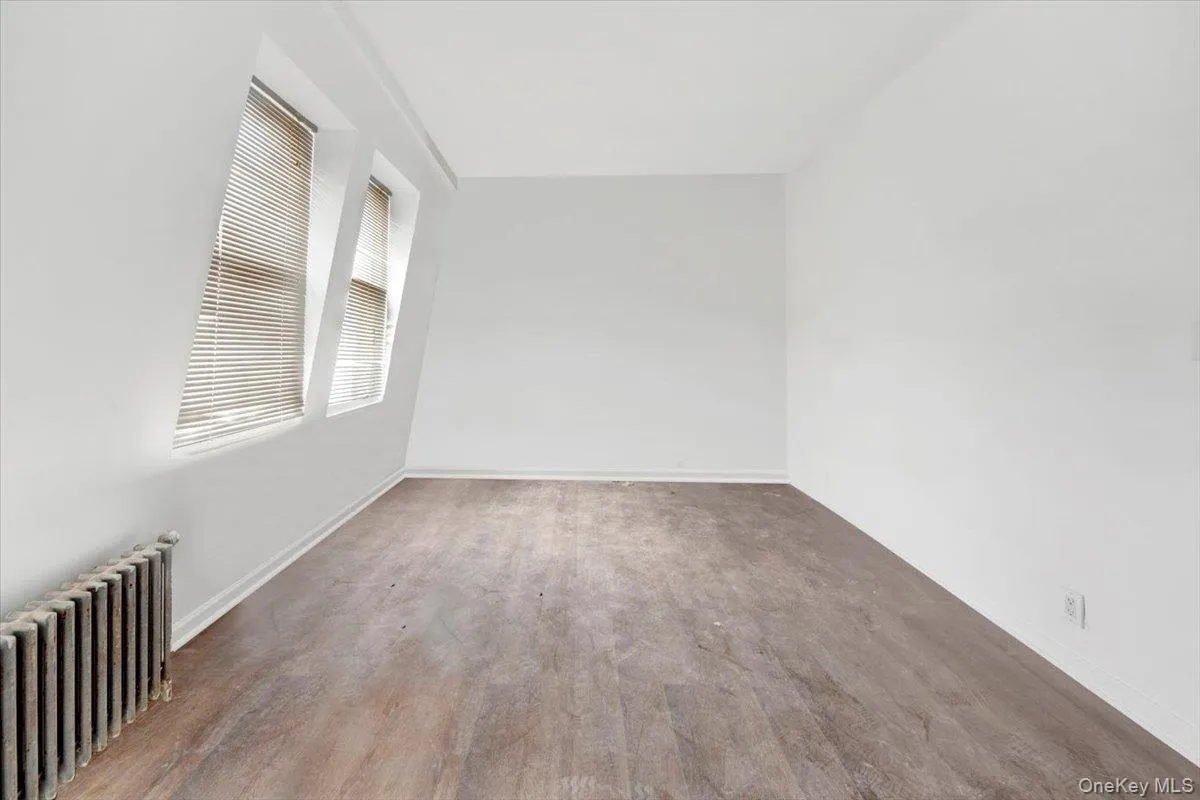 Empty room featuring radiator heating unit and baseboards Empty room featuring radiator heating unit and baseboards