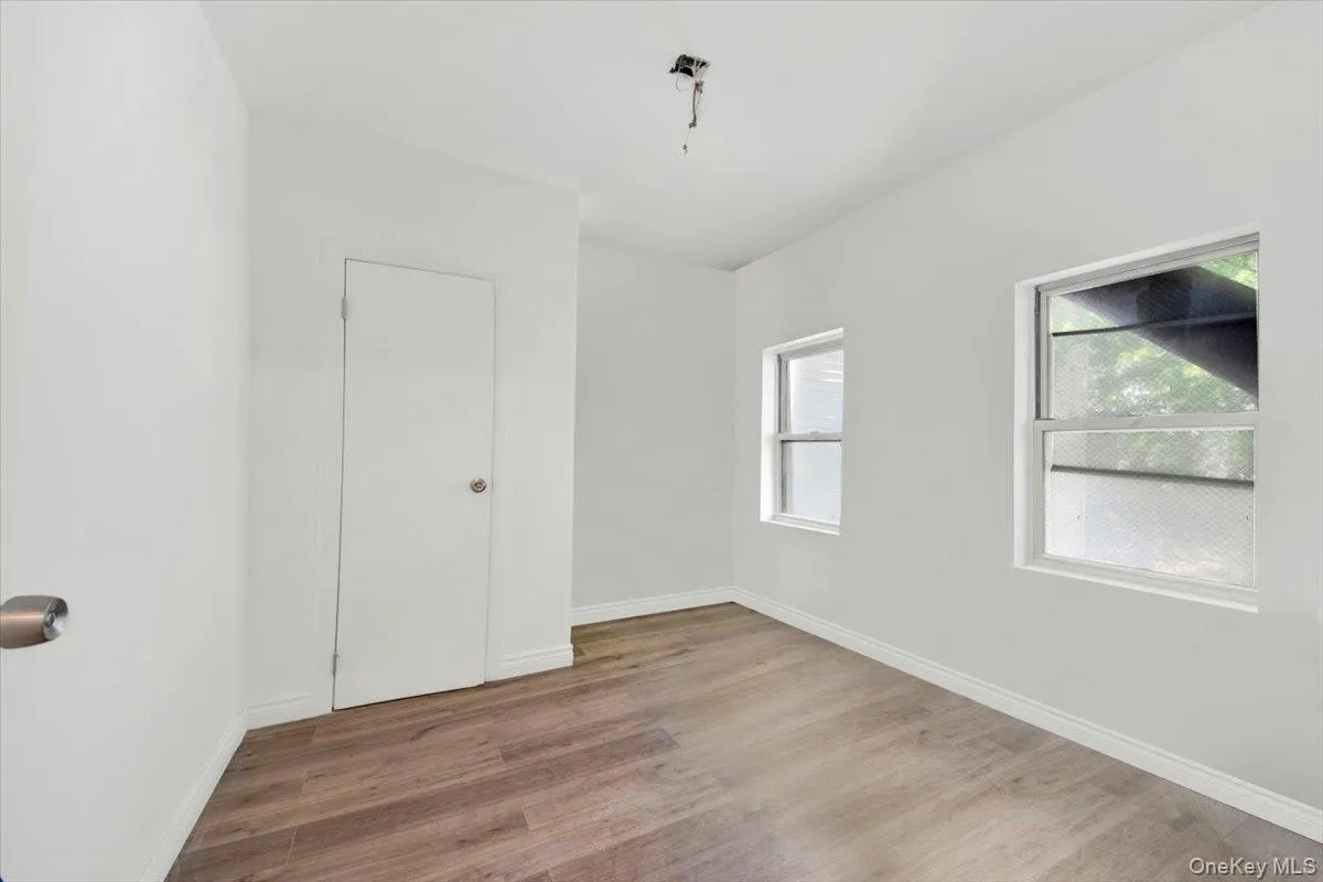 Unfurnished room featuring wood finished floors, plenty of natural light, and baseboards Unfurnished room featuring wood finished floors, plenty of natural light, and baseboards