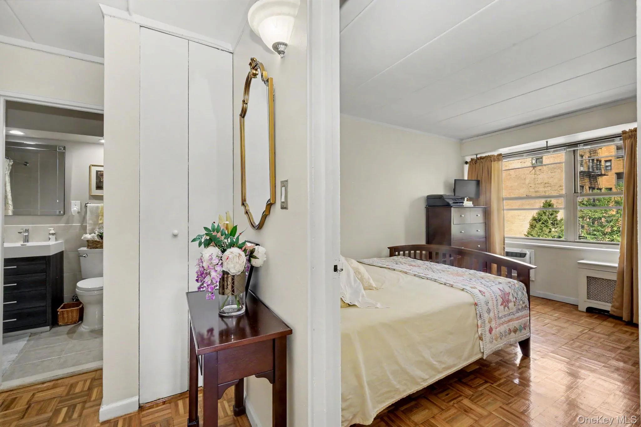 Bedroom with Hardwood Flooring, Ensuite Bathroom Access, and Abundant Natural LightThis generously proportioned bedroom features warm wood-finish flooring, direct access to an ensuite bathroom, and multiple windows with natural wood frames that flood the space with daylight Bedroom with Hardwood Flooring, Ensuite Bathroom Access, and Abundant Natural LightThis generously proportioned bedroom features warm wood-finish flooring, direct access to an ensuite bathroom, and multiple windows with natural wood frames that flood the space with daylight