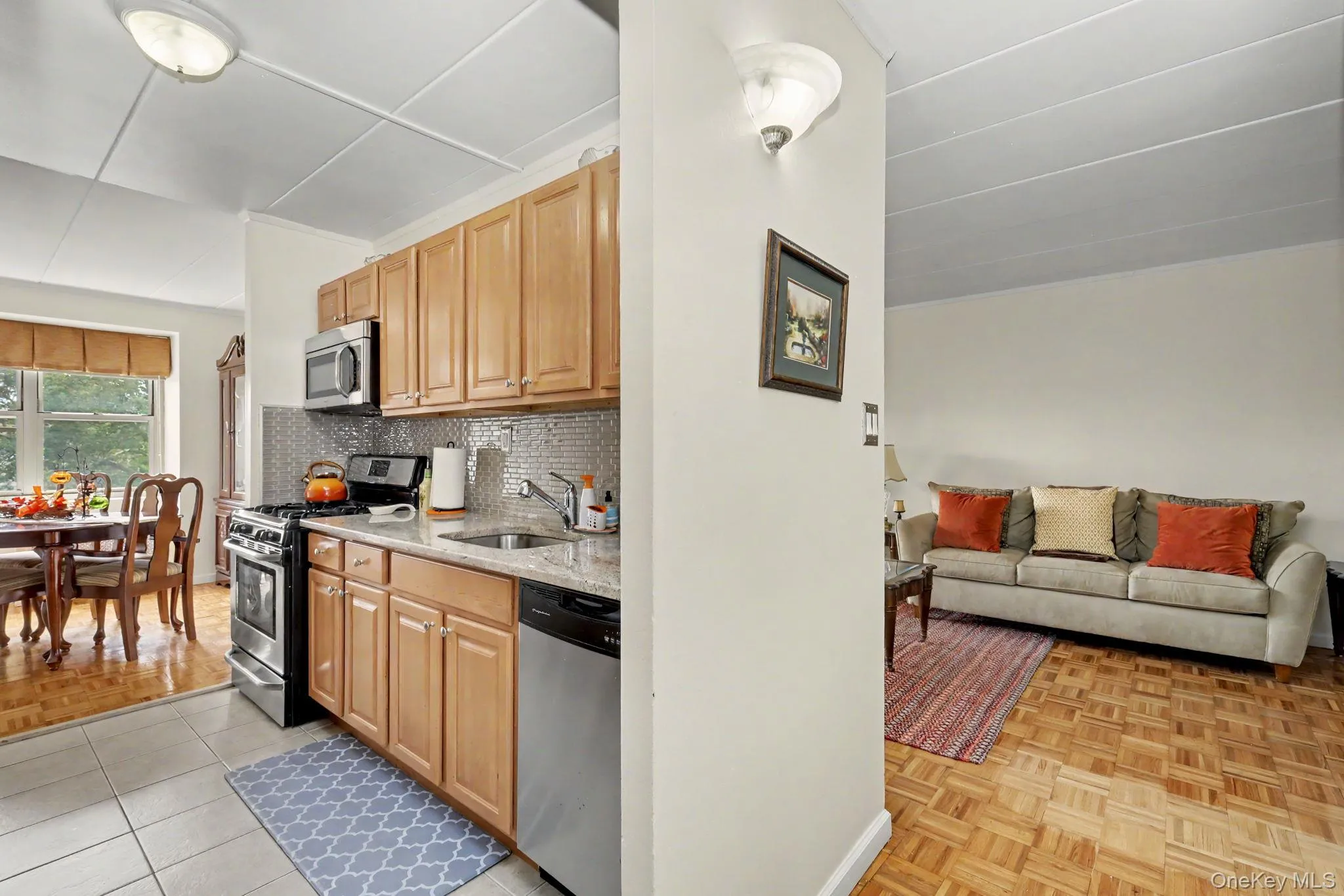 Kitchen featuring wood-finish cabinetry, stainless steel appliances, a tiled backsplash, and stone-finish countertops Kitchen featuring wood-finish cabinetry, stainless steel appliances, a tiled backsplash, and stone-finish countertops