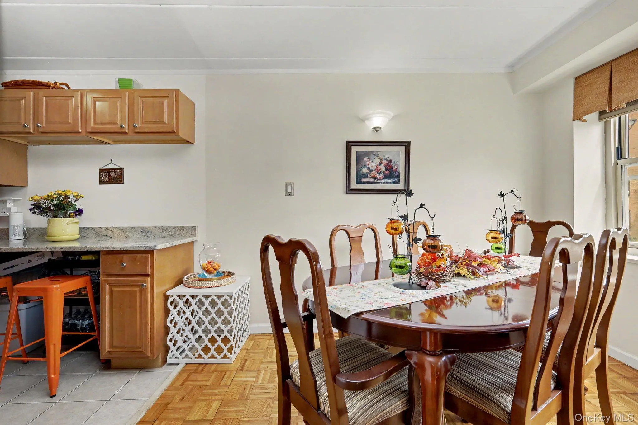 Hardwood flooring, crown molding, wall sconce lighting, and kitchen pass-through with granite-style countertop and wood cabinetry Hardwood flooring, crown molding, wall sconce lighting, and kitchen pass-through with granite-style countertop and wood cabinetry