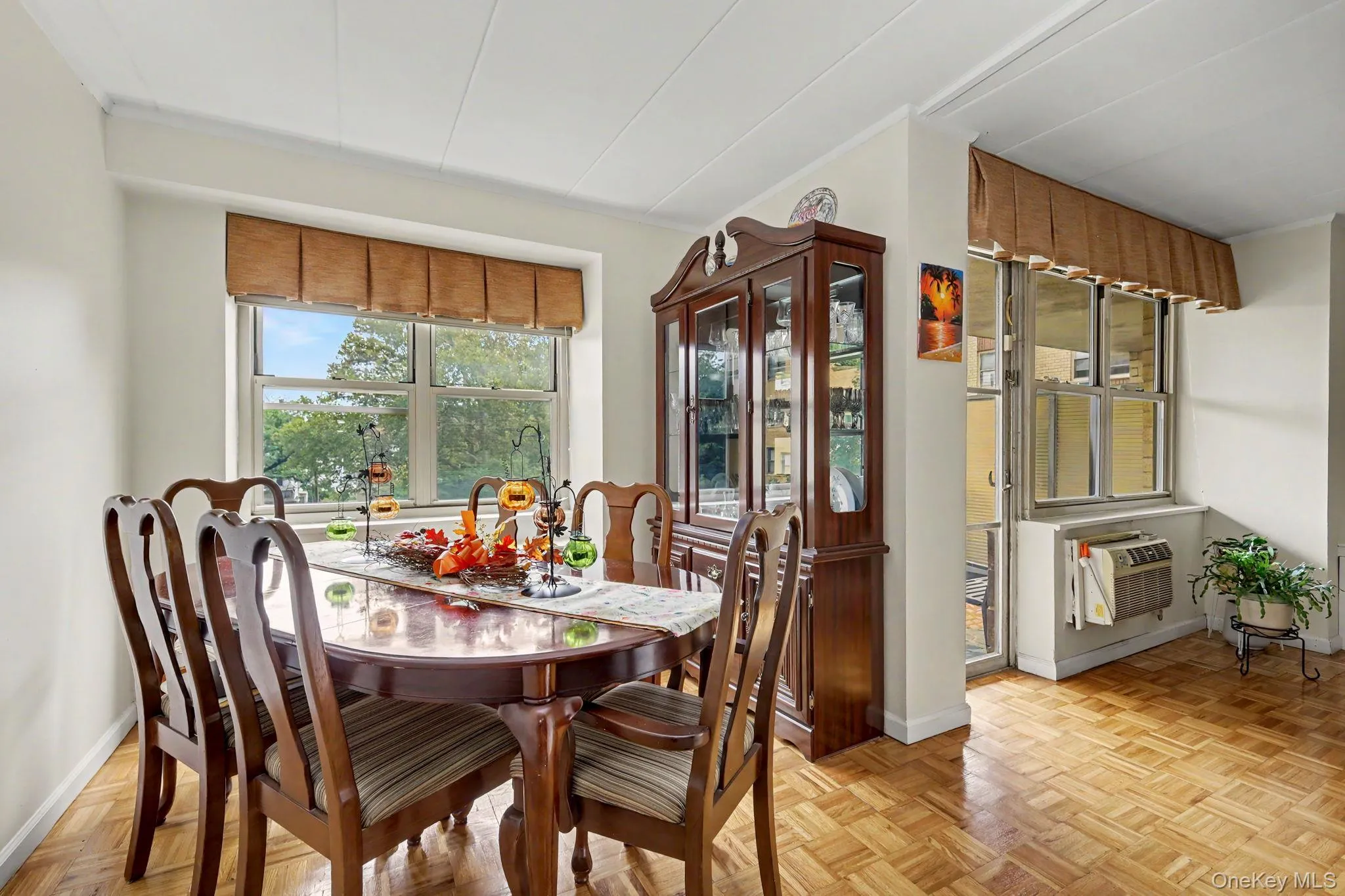 Parquet wood-finish flooring, large window with outdoor scenery, additional window bank, and a built-in air conditioning unit Parquet wood-finish flooring, large window with outdoor scenery, additional window bank, and a built-in air conditioning unit