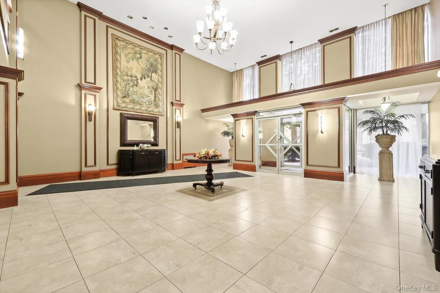 Welcoming Lobby with tile flooring, chandelier lighting, and decorative wall paneling with wood trim Welcoming Lobby with tile flooring, chandelier lighting, and decorative wall paneling with wood trim