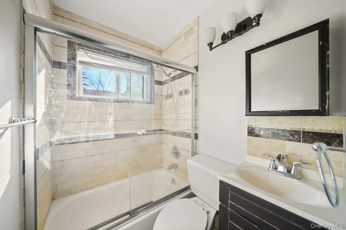 Full bathroom with enclosed tub / shower combo, vanity, and tasteful backsplash Full bathroom with enclosed tub / shower combo, vanity, and tasteful backsplash
