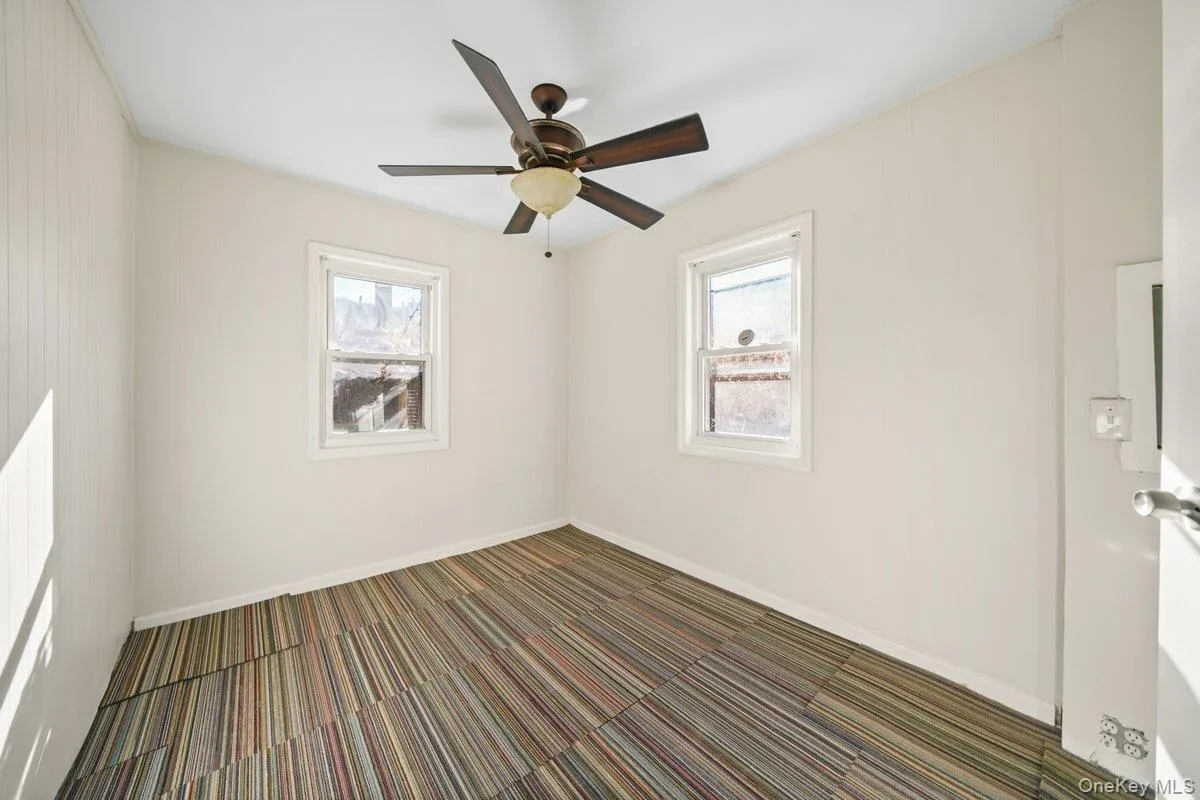 Spare room featuring dark carpet, healthy amount of natural light, and a ceiling fan Spare room featuring dark carpet, healthy amount of natural light, and a ceiling fan