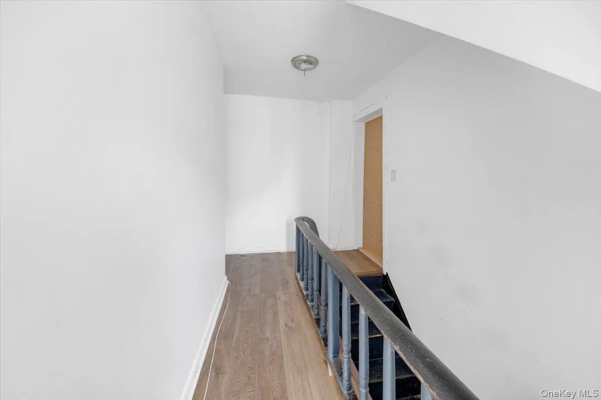 Corridor with an upstairs landing, wood finished floors, and baseboards Corridor with an upstairs landing, wood finished floors, and baseboards