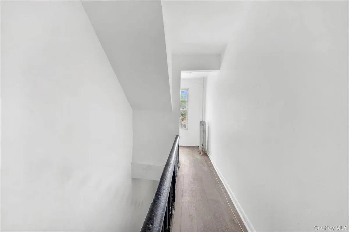Corridor featuring radiator heating unit, wood finished floors, an upstairs landing, vaulted ceiling, and baseboards Corridor featuring radiator heating unit, wood finished floors, an upstairs landing, vaulted ceiling, and baseboards