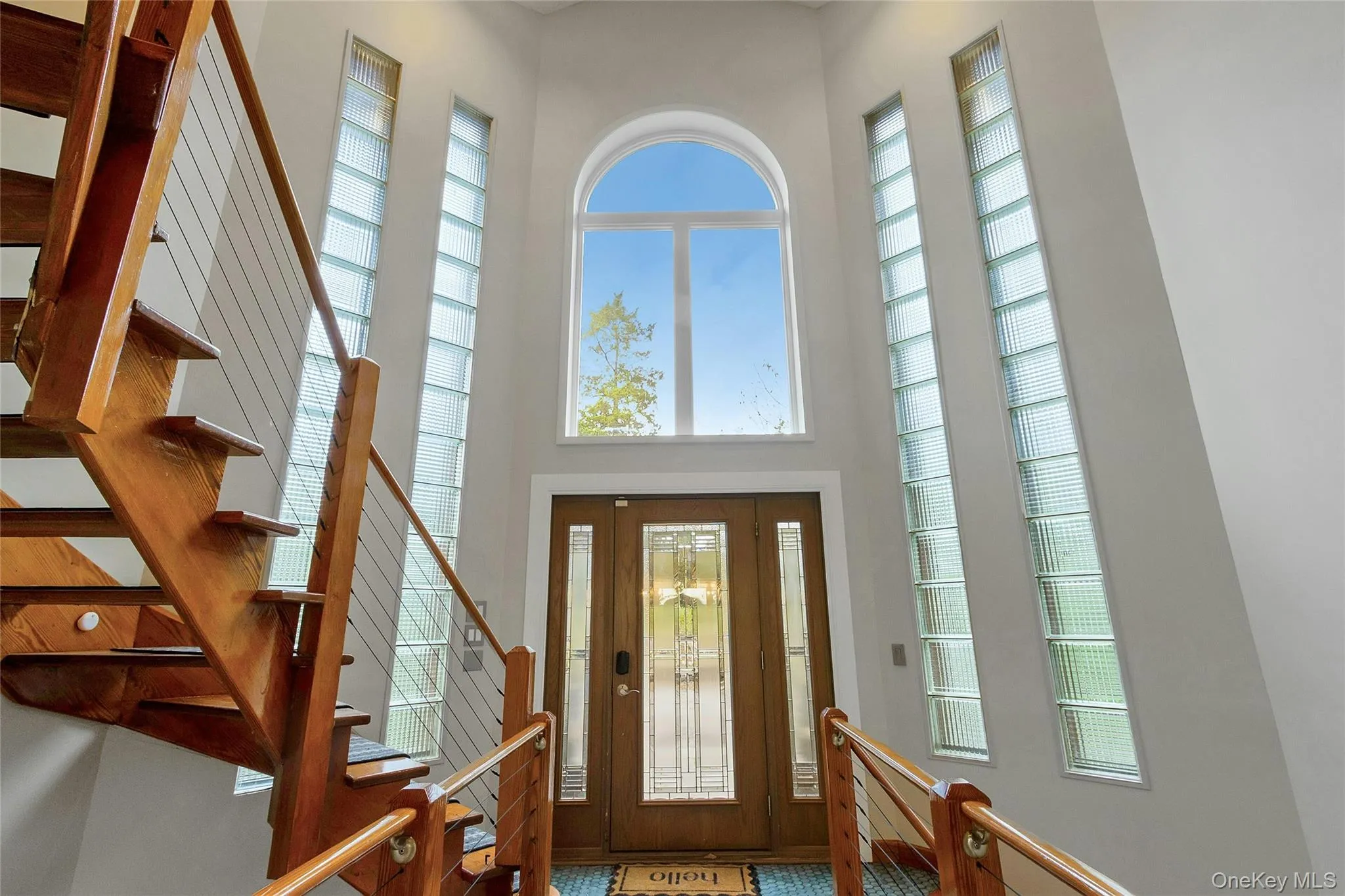 Two-story foyer with an arched transom window, two-panel wood entry door, and vertical glass block windows Two-story foyer with an arched transom window, two-panel wood entry door, and vertical glass block windows