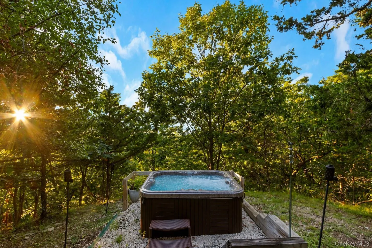 Outdoor hot tub with integrated steps, surrounded by natural landscaping and mature trees Outdoor hot tub with integrated steps, surrounded by natural landscaping and mature trees