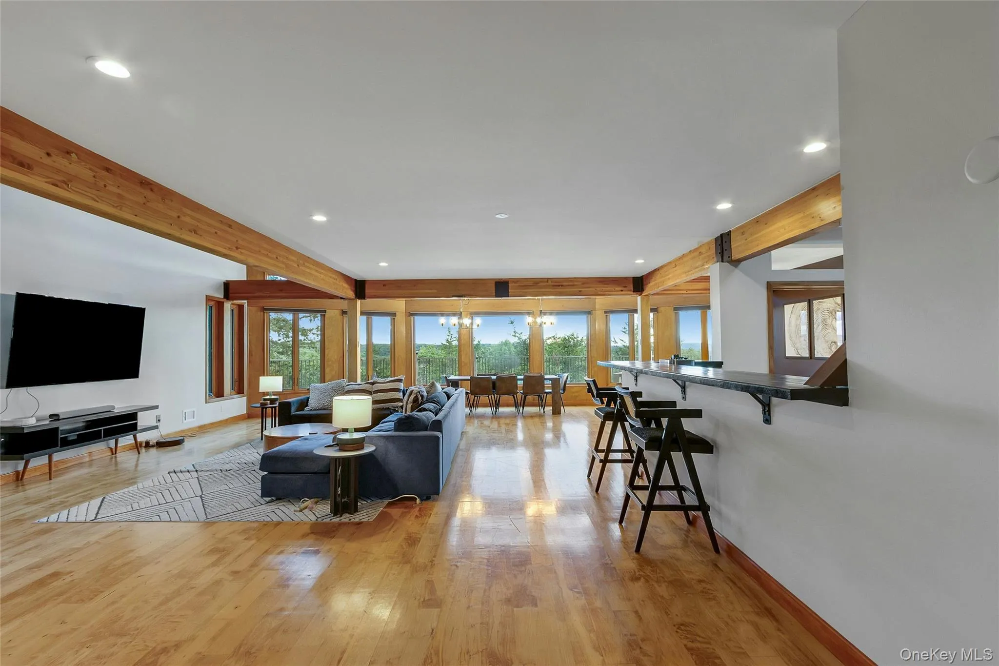Hardwood flooring, exposed wooden beams, recessed lighting, expansive windows, and a built-in bar Hardwood flooring, exposed wooden beams, recessed lighting, expansive windows, and a built-in bar