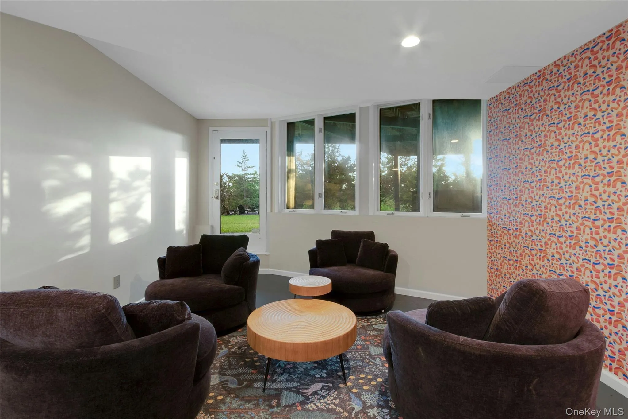 Vaulted ceiling, recessed lighting, exterior access door, a wall of multiple windows, and accent wall with patterned wall covering Vaulted ceiling, recessed lighting, exterior access door, a wall of multiple windows, and accent wall with patterned wall covering