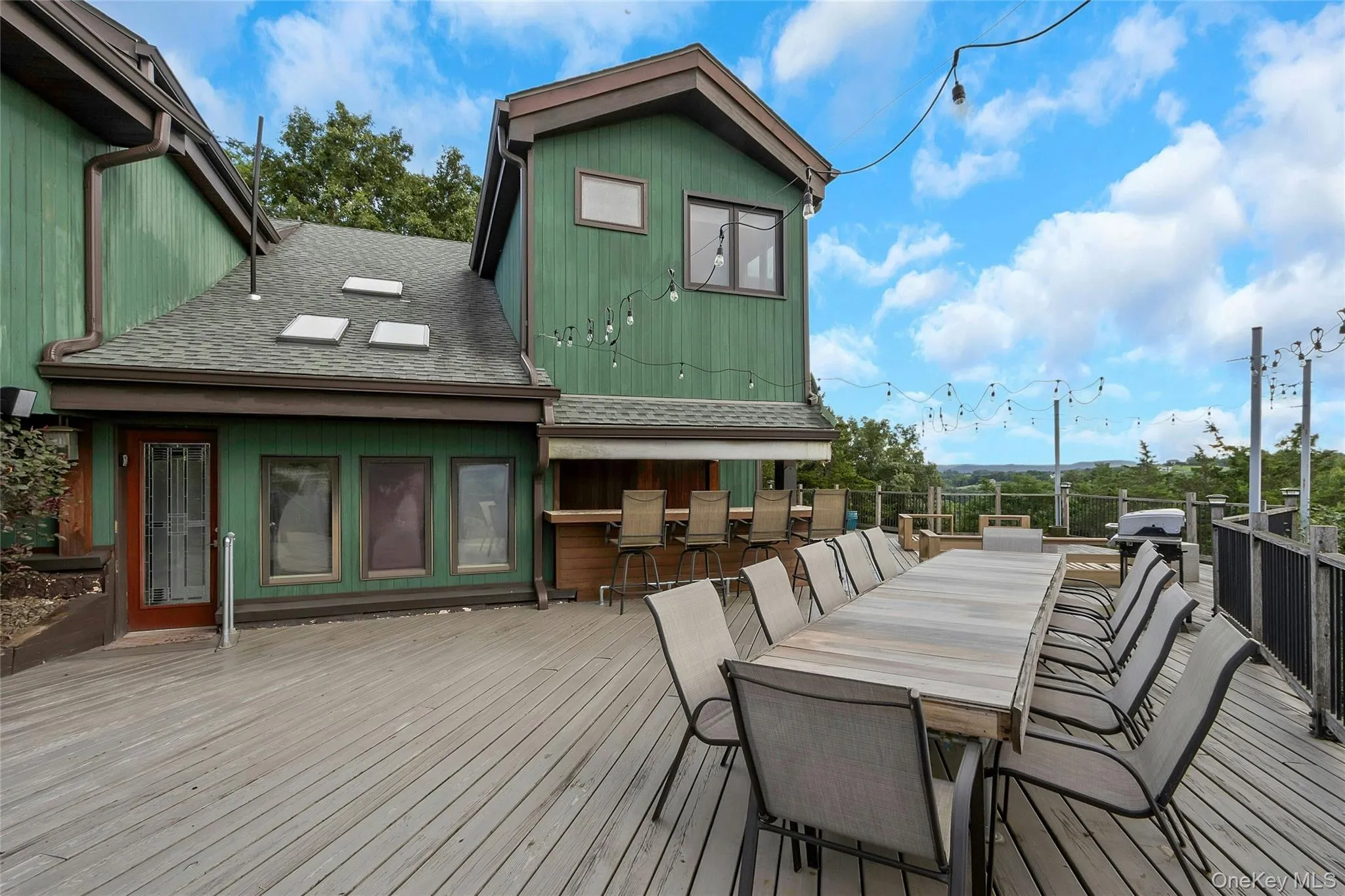 Expansive outdoor deck featuring a built-in bar, extensive railing, and string lighting Expansive outdoor deck featuring a built-in bar, extensive railing, and string lighting