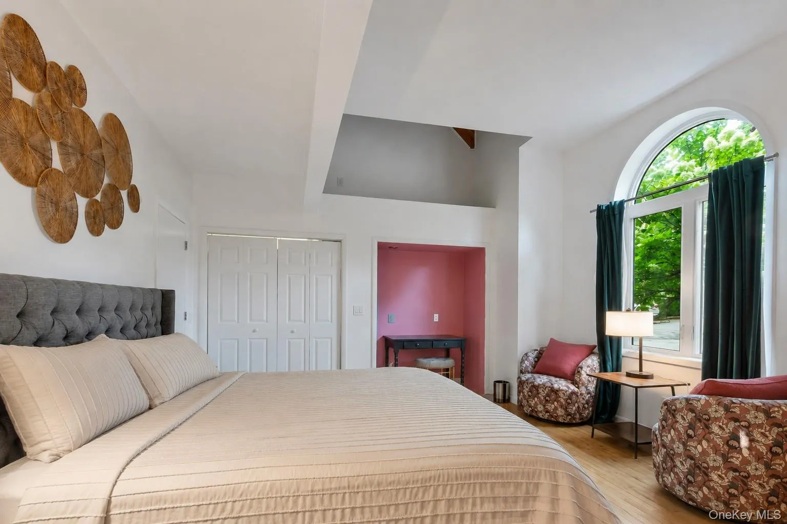 Arched window, wood-finish flooring, white paneled bifold closet doors, built-in recessed area, and a tray ceiling with an angled skylight Arched window, wood-finish flooring, white paneled bifold closet doors, built-in recessed area, and a tray ceiling with an angled skylight
