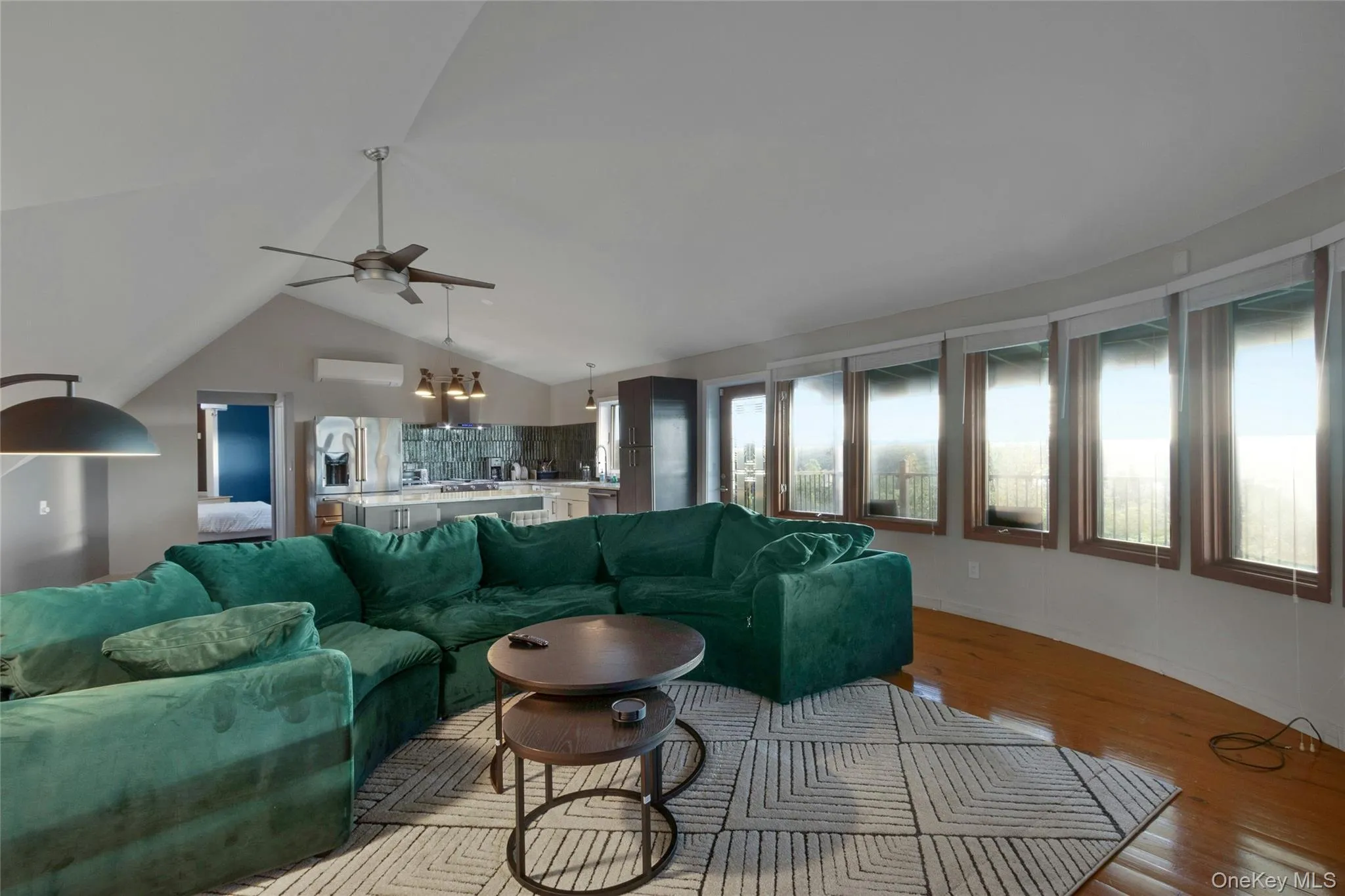 Vaulted ceiling with a ceiling fan, wood-finish flooring, and a wall of windows Vaulted ceiling with a ceiling fan, wood-finish flooring, and a wall of windows