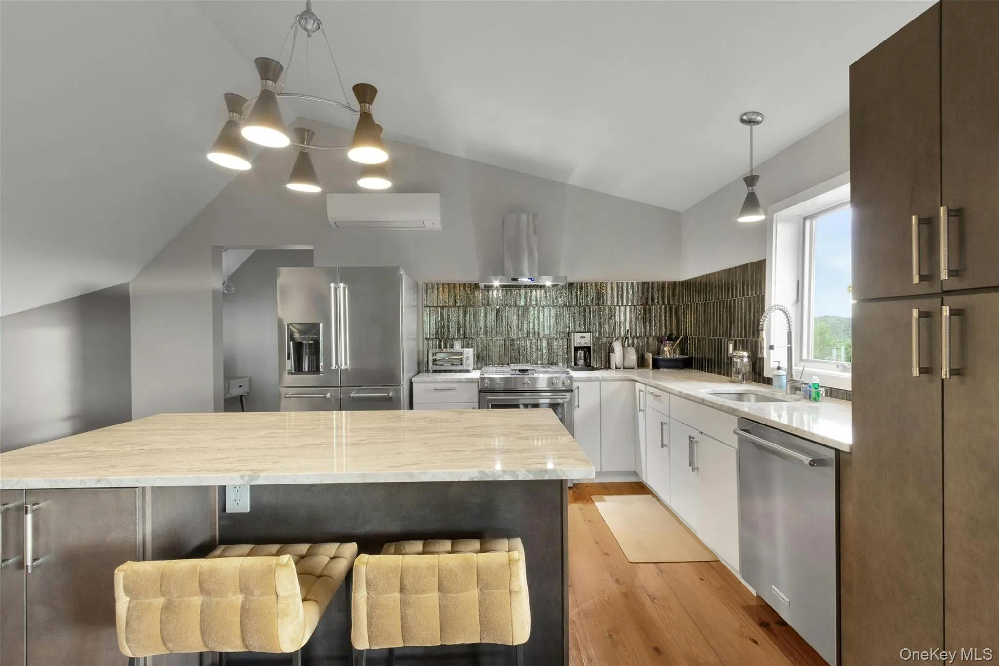 Spacious kitchen featuring an angled ceiling, large center island with stone countertop, stainless steel appliances, and a tiled backsplash Spacious kitchen featuring an angled ceiling, large center island with stone countertop, stainless steel appliances, and a tiled backsplash