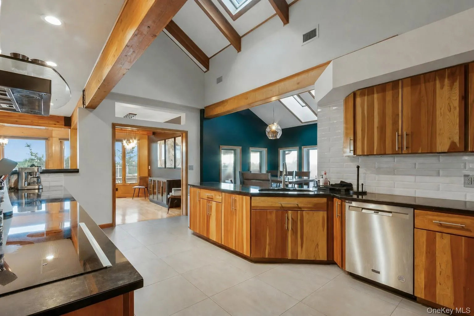 Vaulted ceilings with exposed wood beams, skylights, wood-finish cabinetry, stainless steel appliances, and a subway tile backsplash Vaulted ceilings with exposed wood beams, skylights, wood-finish cabinetry, stainless steel appliances, and a subway tile backsplash