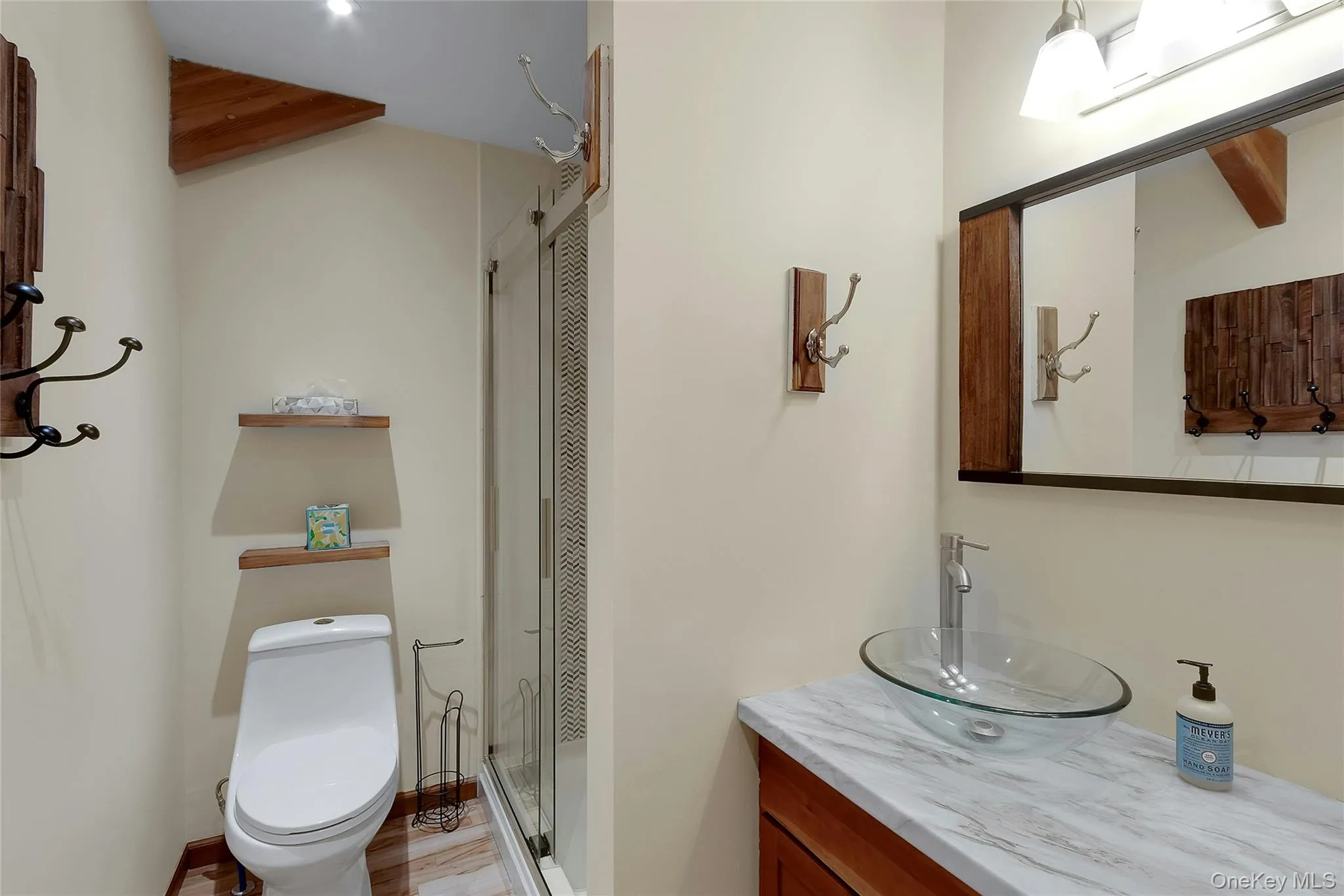 Bathroom featuring a vessel sink, a shower with a clear glass enclosure, and a vanity with a light-toned countertop Bathroom featuring a vessel sink, a shower with a clear glass enclosure, and a vanity with a light-toned countertop