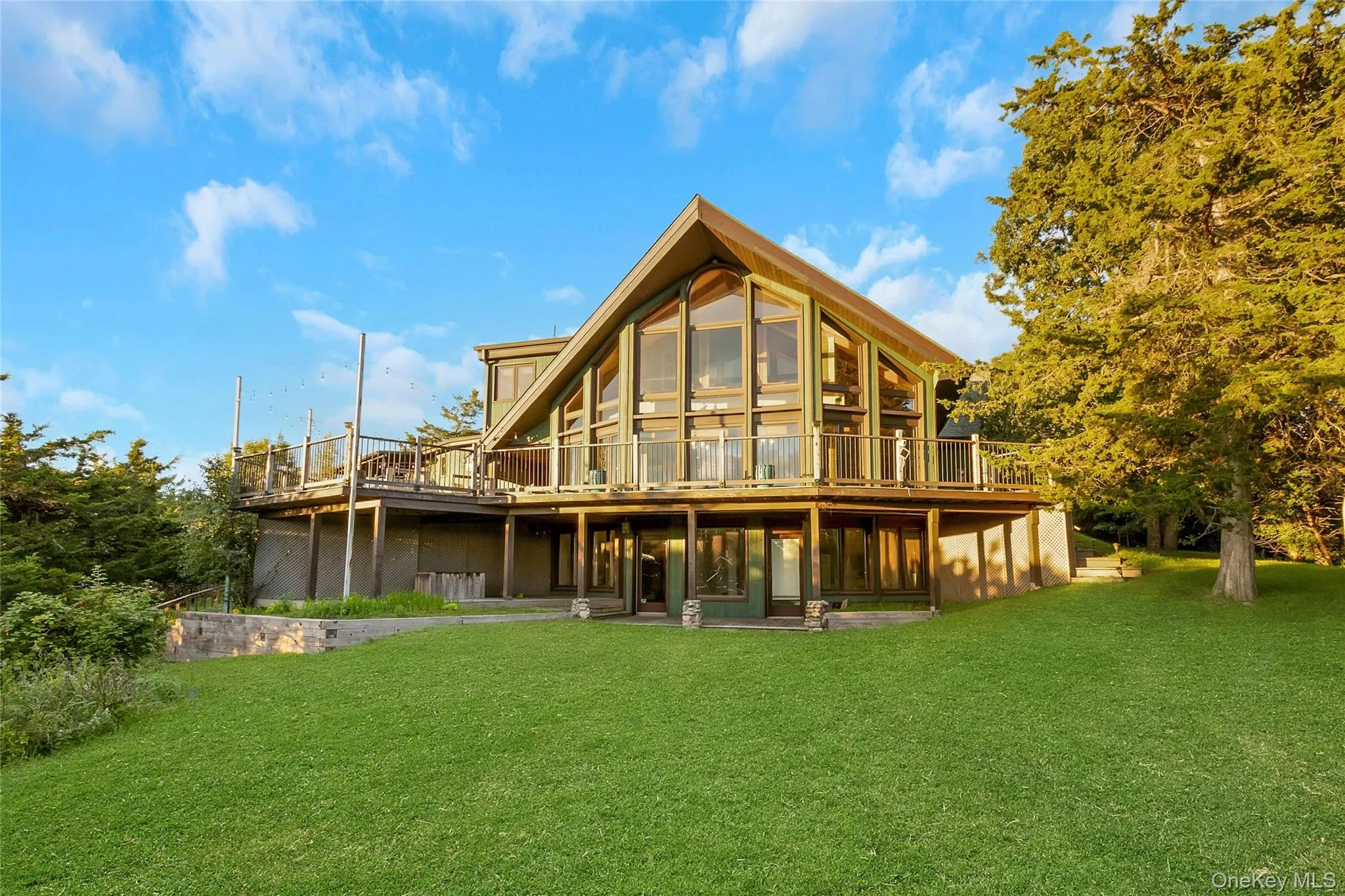 A-frame architectural style with extensive glazing, elevated outdoor decking, and ground-level access A-frame architectural style with extensive glazing, elevated outdoor decking, and ground-level access