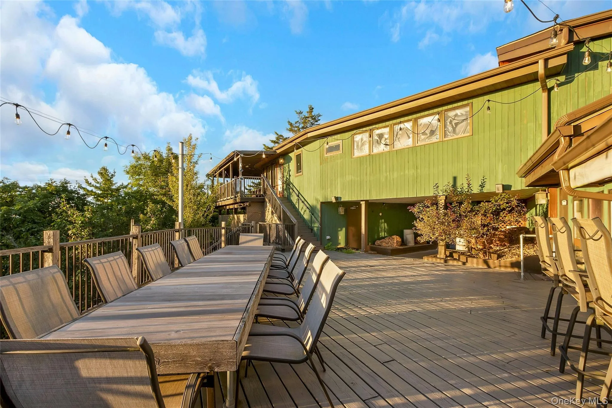 Expansive outdoor decking, multi-level structure, horizontal wood siding, upper-level balcony, and mature trees Expansive outdoor decking, multi-level structure, horizontal wood siding, upper-level balcony, and mature trees