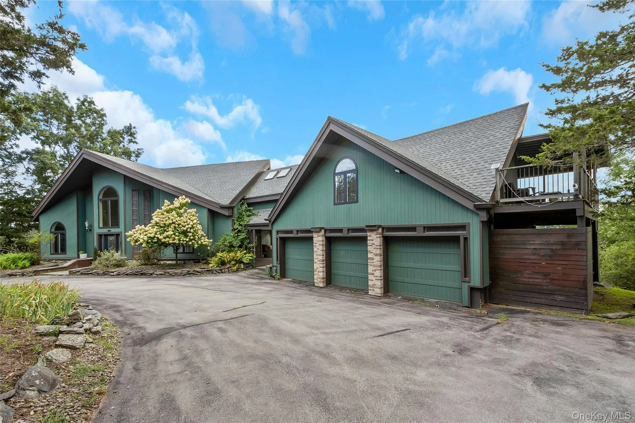 Contemporary exterior with a multi-level roofline, attached three-car garage, upper-level balcony, and a paved driveway Contemporary exterior with a multi-level roofline, attached three-car garage, upper-level balcony, and a paved driveway