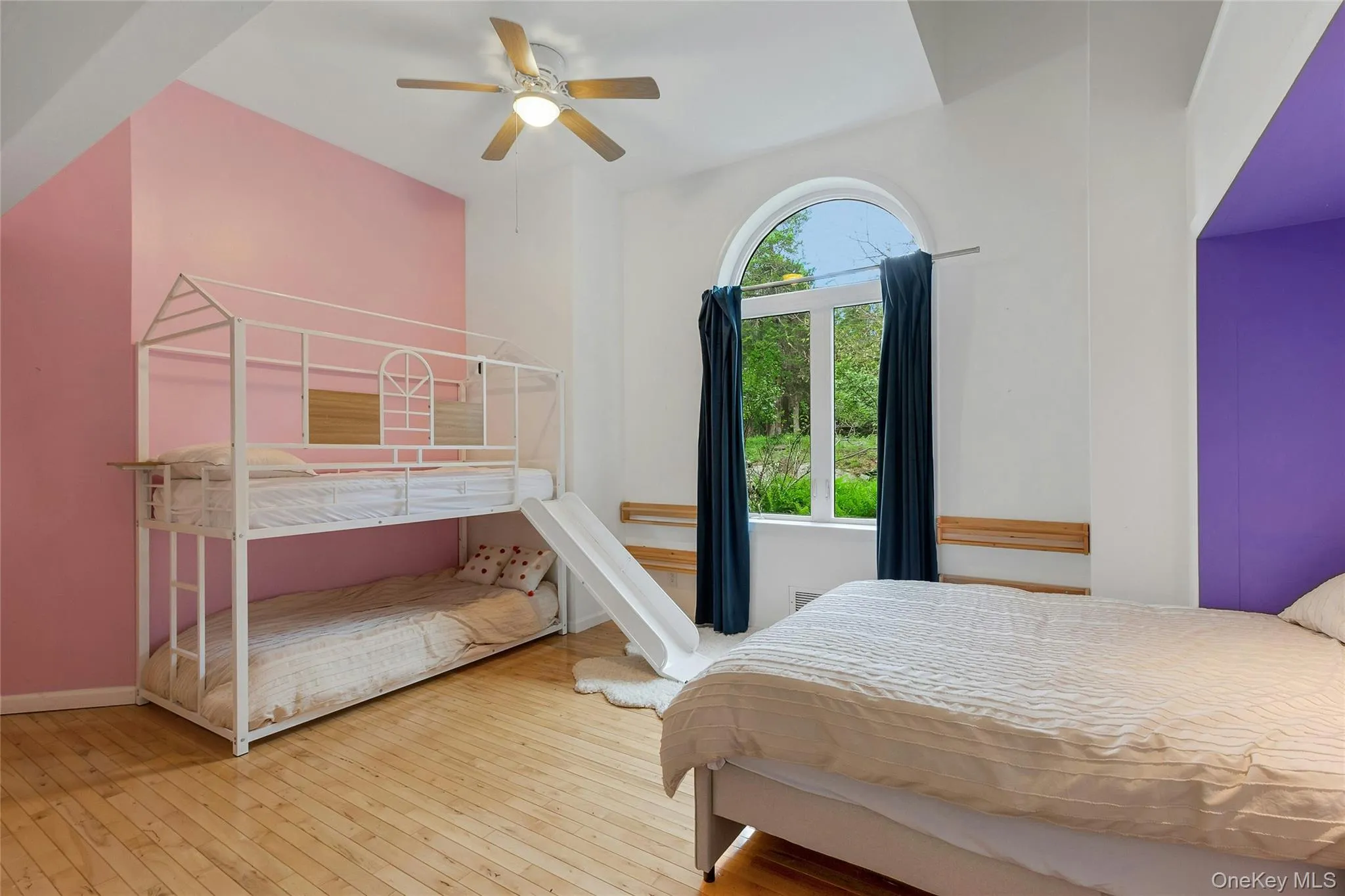 Arched window, wood-finish flooring, ceiling fan, and built-in alcove Arched window, wood-finish flooring, ceiling fan, and built-in alcove