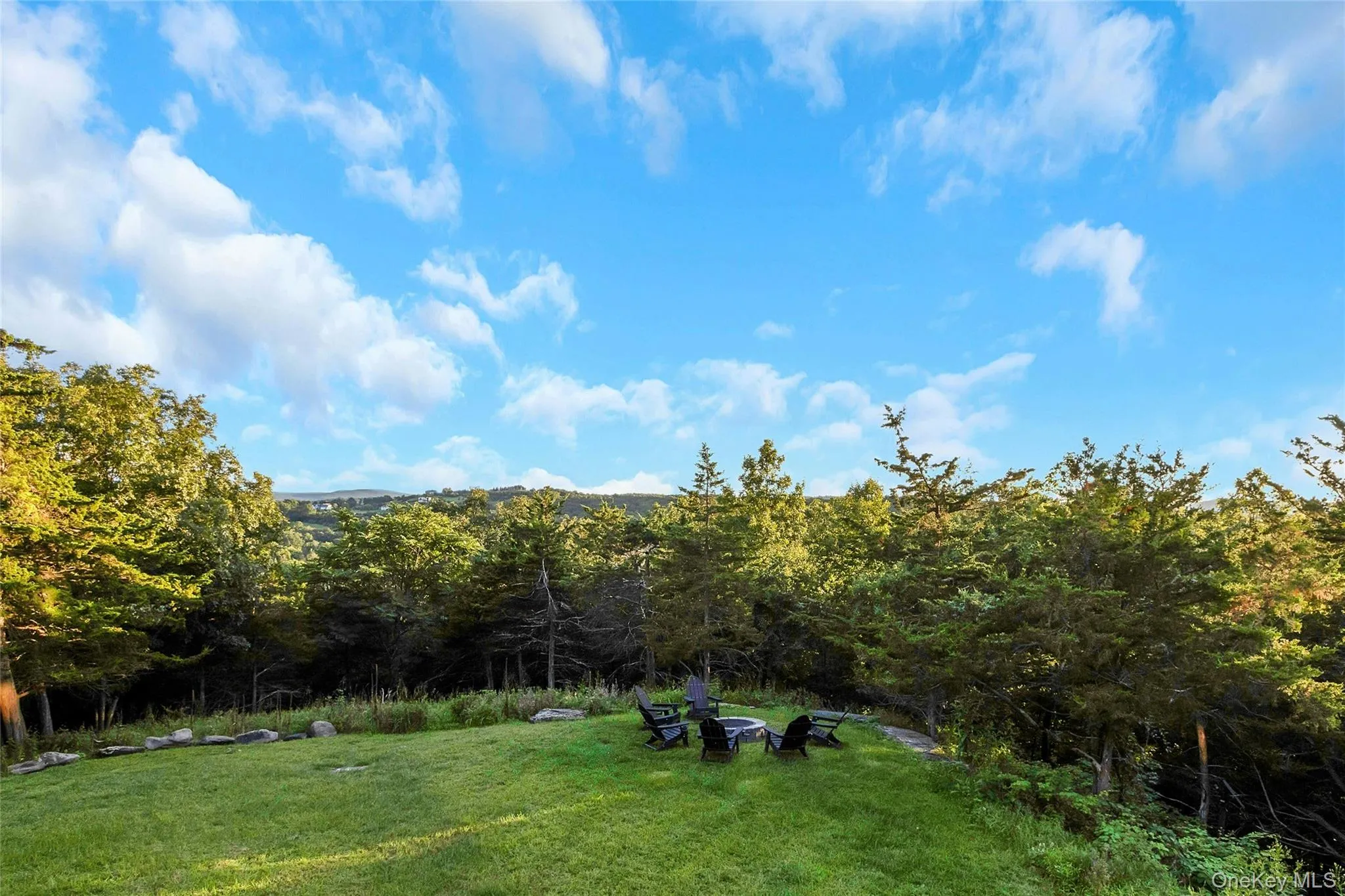 Expansive lawn with a built-in fire pit, surrounded by mature trees and natural landscaping Expansive lawn with a built-in fire pit, surrounded by mature trees and natural landscaping