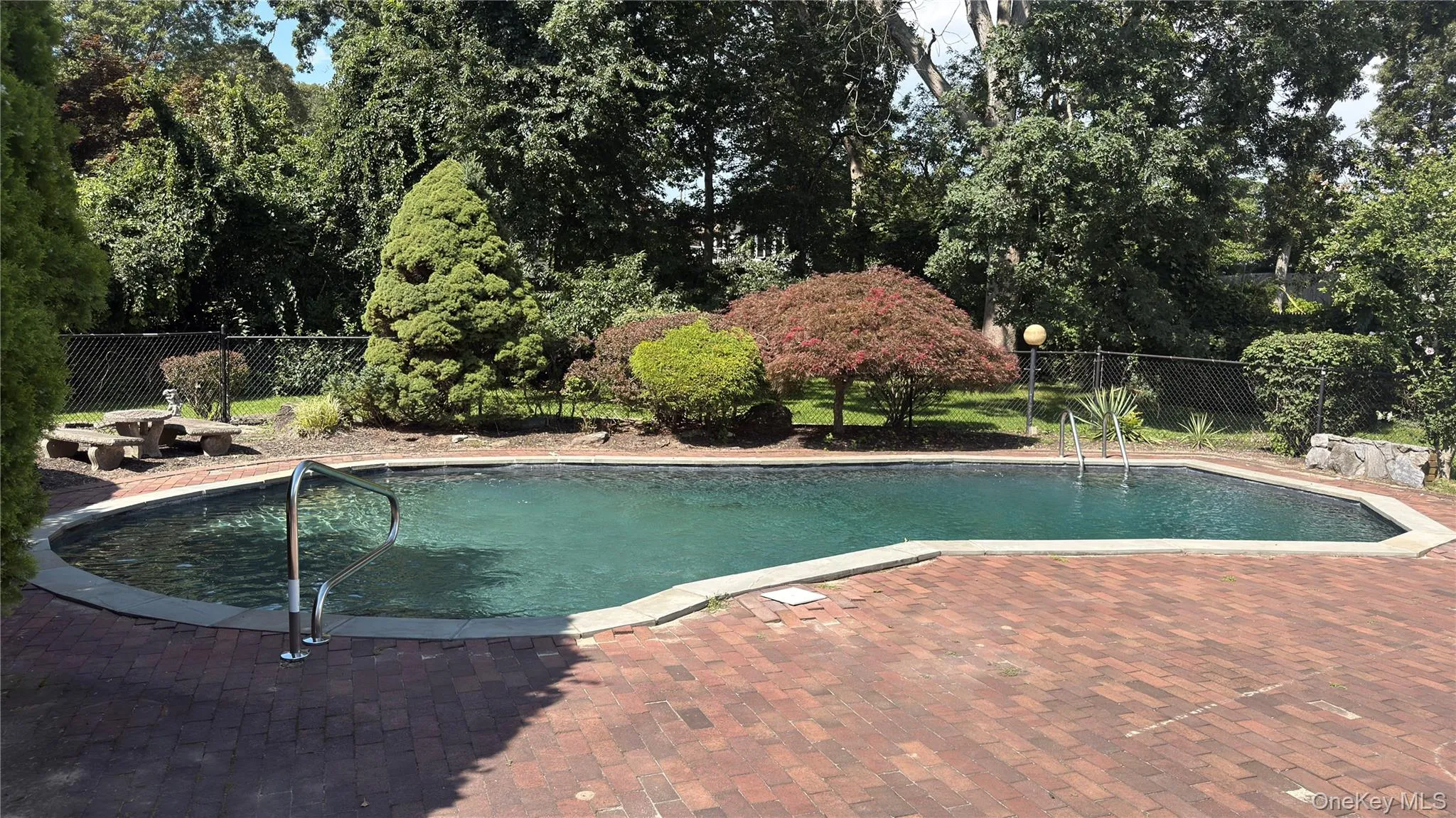 Gunite swimming pool with brick paver surround, stainless steel handrails, and a concrete coping Gunite swimming pool with brick paver surround, stainless steel handrails, and a concrete coping