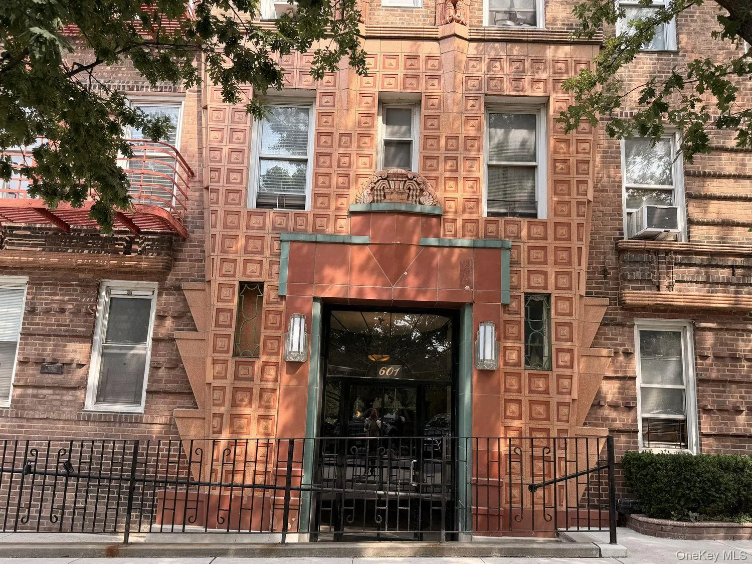 Building exterior featuring terracotta-toned decorative tiles, brick facade, and a metal security gate Building exterior featuring terracotta-toned decorative tiles, brick facade, and a metal security gate