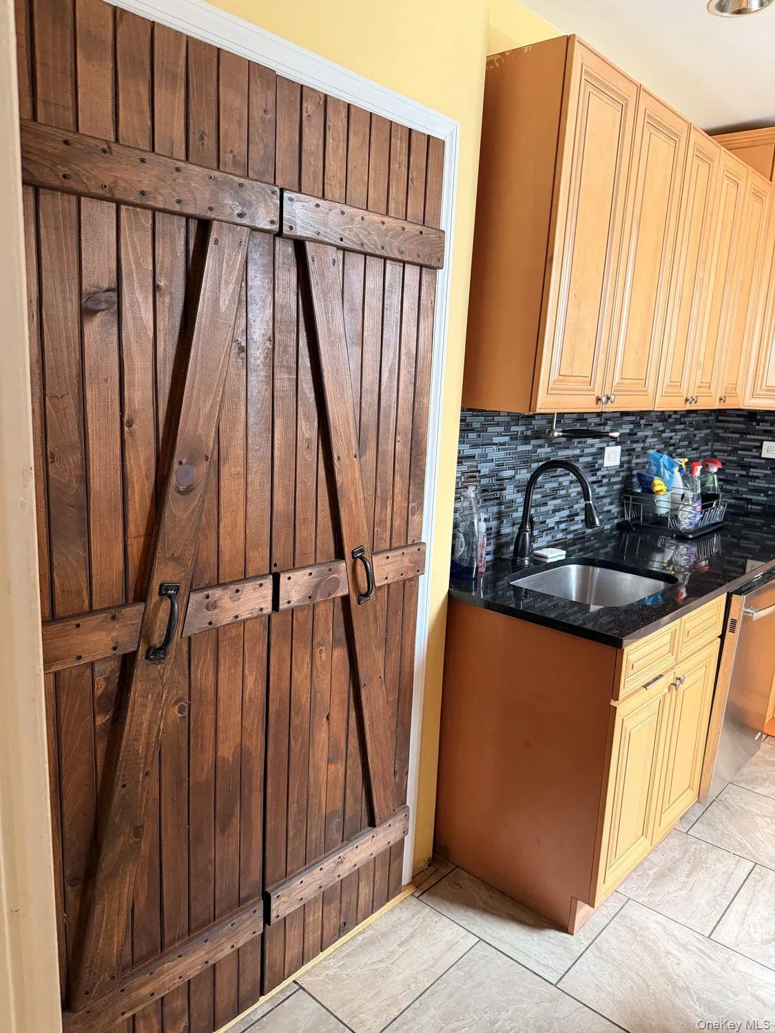 Wood-plank double doors with iron-finish hardware, subway tile backsplash, and dark countertop Wood-plank double doors with iron-finish hardware, subway tile backsplash, and dark countertop