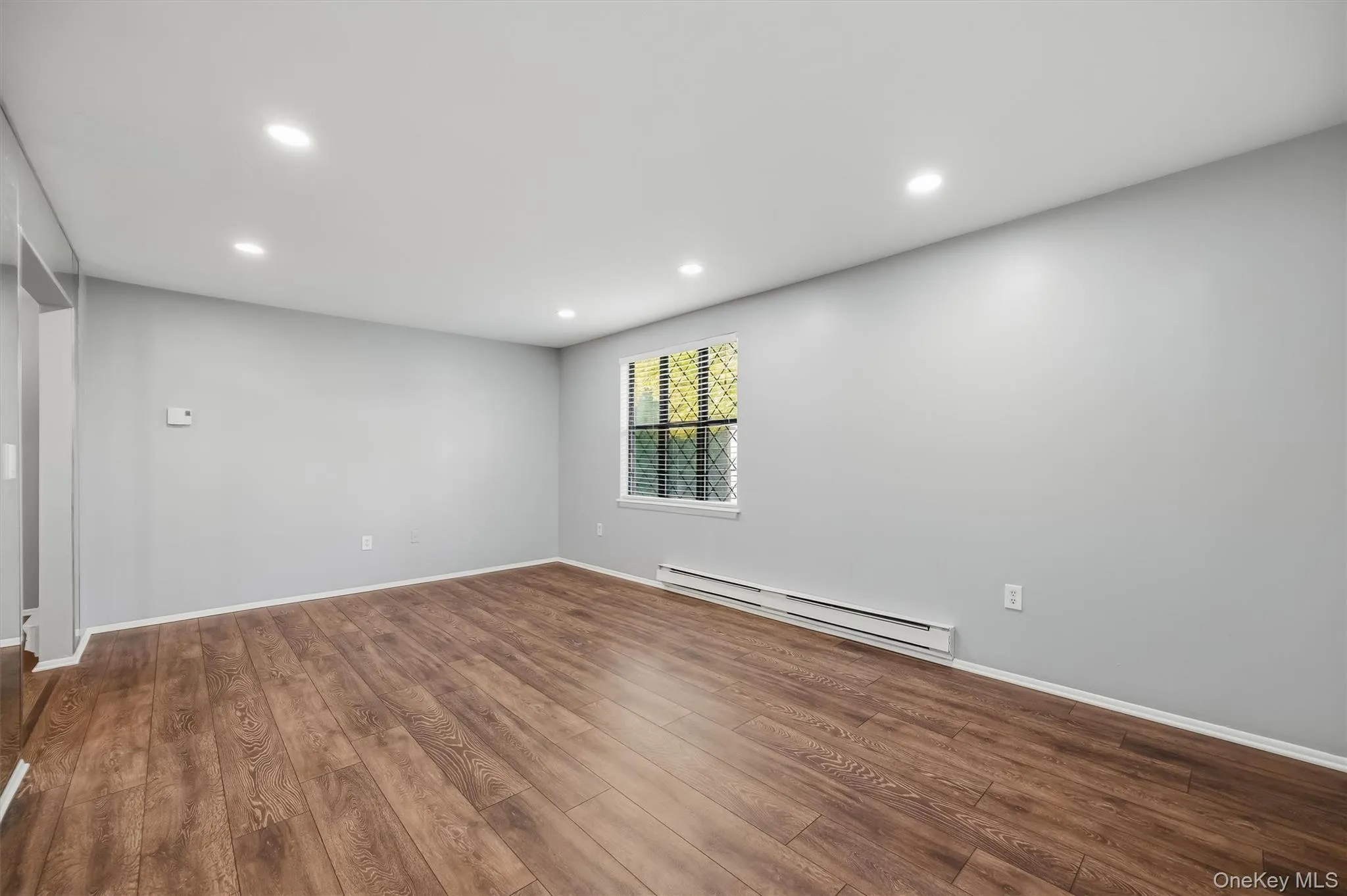 Another view of the spacious living room with recessed lighting and wood-style flooring. Another view of the spacious living room with recessed lighting and wood-style flooring.