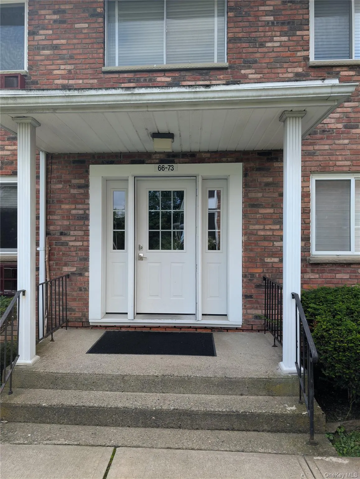 Brick exterior featuring a covered entry, white paneled door with glass inserts, and concrete steps with wrought iron railings Brick exterior featuring a covered entry, white paneled door with glass inserts, and concrete steps with wrought iron railings