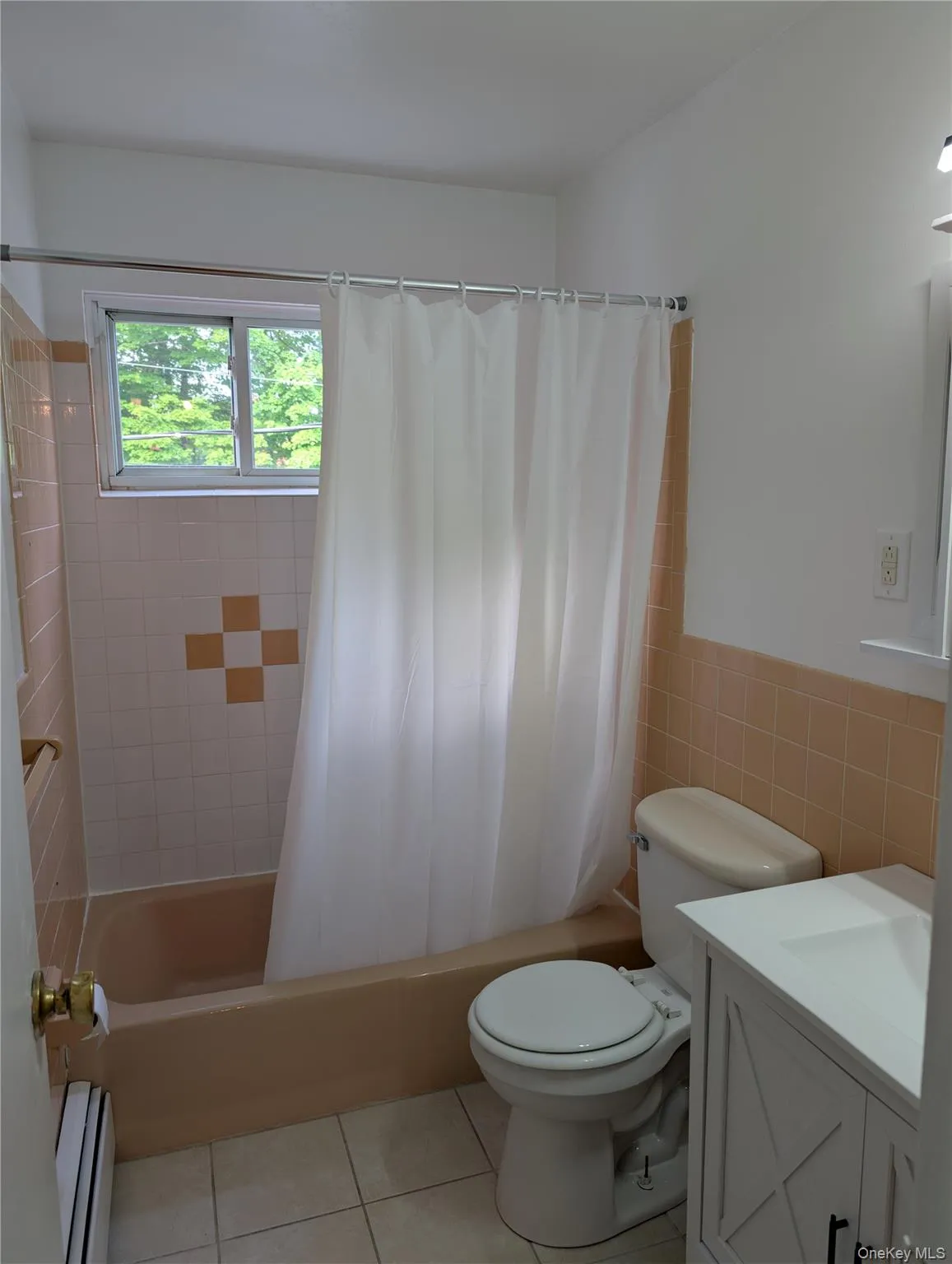 Bathroom featuring a built-in tub, tiled walls, and a window Bathroom featuring a built-in tub, tiled walls, and a window