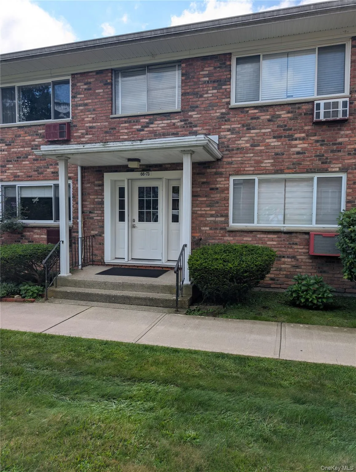Brick exterior with multiple windows, covered entrance, paved walkway, and landscaped shrubbery Brick exterior with multiple windows, covered entrance, paved walkway, and landscaped shrubbery