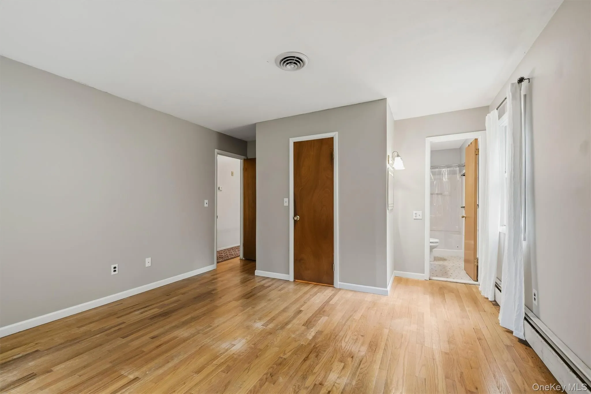 Hardwood flooring, light gray wall tones, wood-paneled doors, and a wall-mounted sconce Hardwood flooring, light gray wall tones, wood-paneled doors, and a wall-mounted sconce