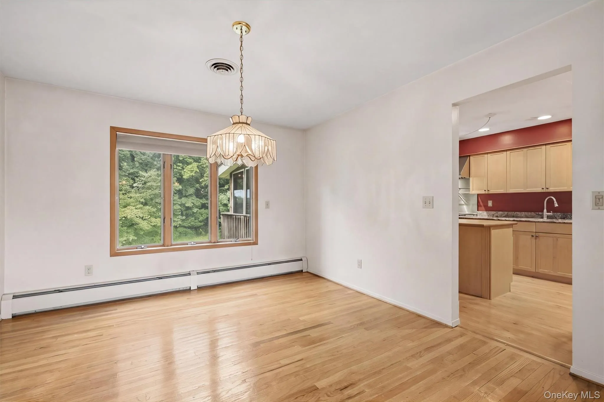 Hardwood flooring, natural wood window trim, pendant light fixture, and baseboard heating Hardwood flooring, natural wood window trim, pendant light fixture, and baseboard heating