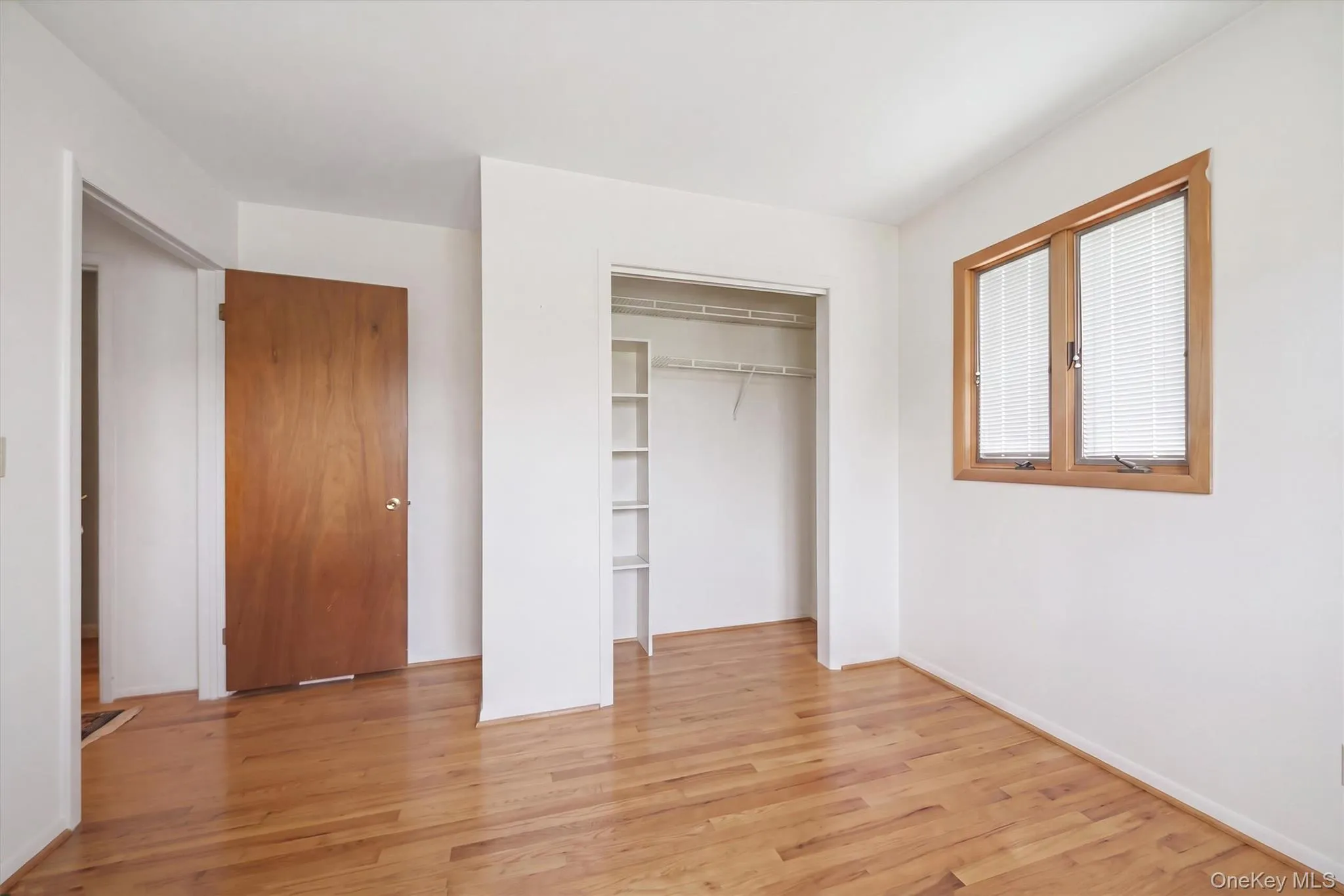 Bedroom 3 Hardwood flooring, white walls, and a window with wood trim Bedroom 3 Hardwood flooring, white walls, and a window with wood trim