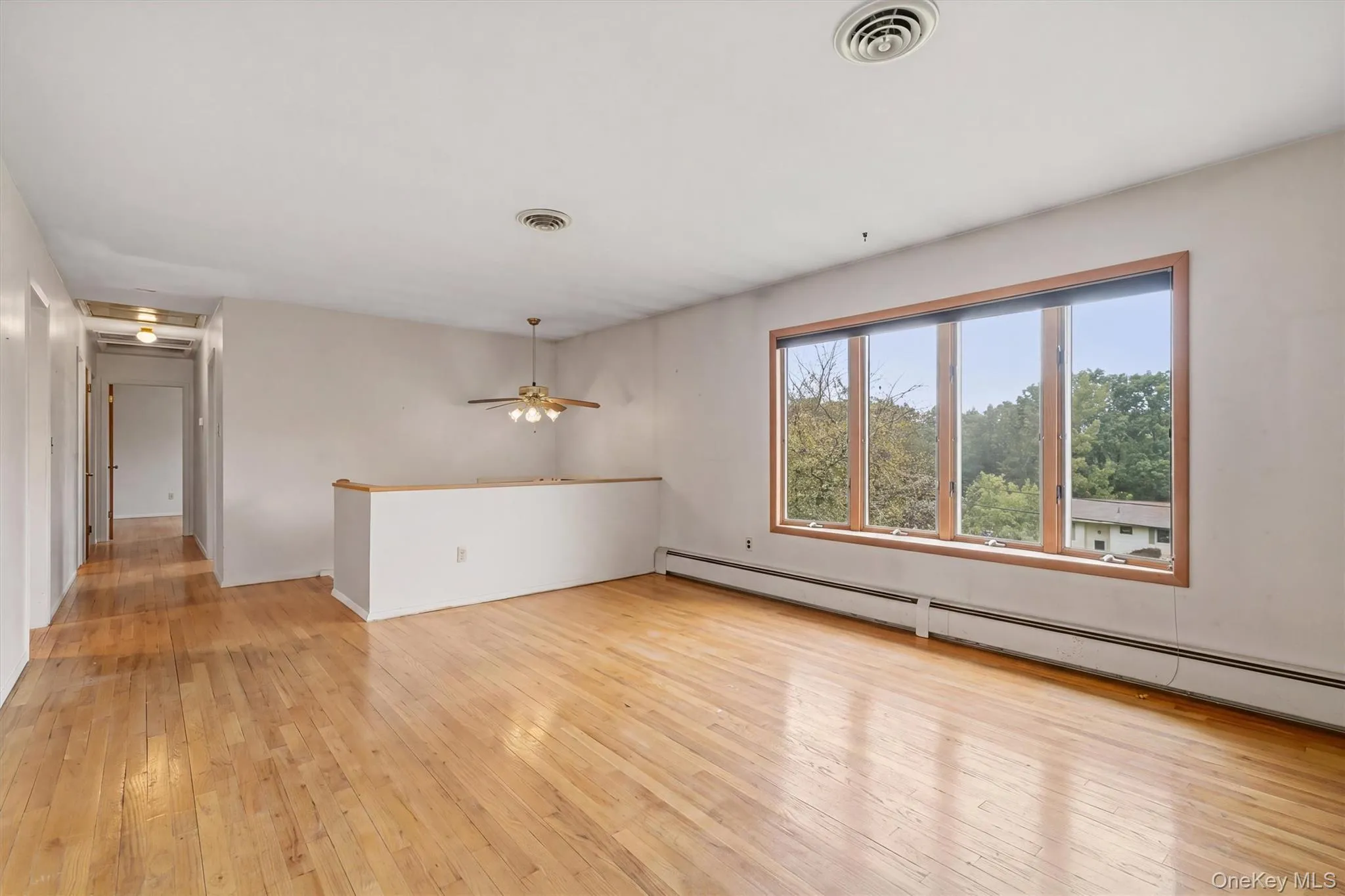 Expansive interior space featuring wood flooring, a multi-pane window with wood-finish trim, Expansive interior space featuring wood flooring, a multi-pane window with wood-finish trim,