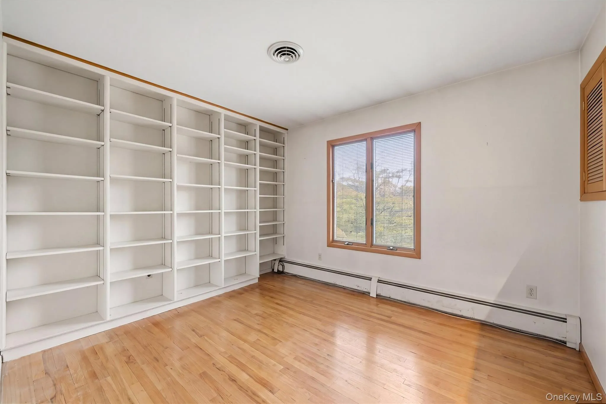 Bedroom 2 -- Extensive built-in shelving, wood-finish flooring, and a large window with wood trim Bedroom 2 -- Extensive built-in shelving, wood-finish flooring, and a large window with wood trim