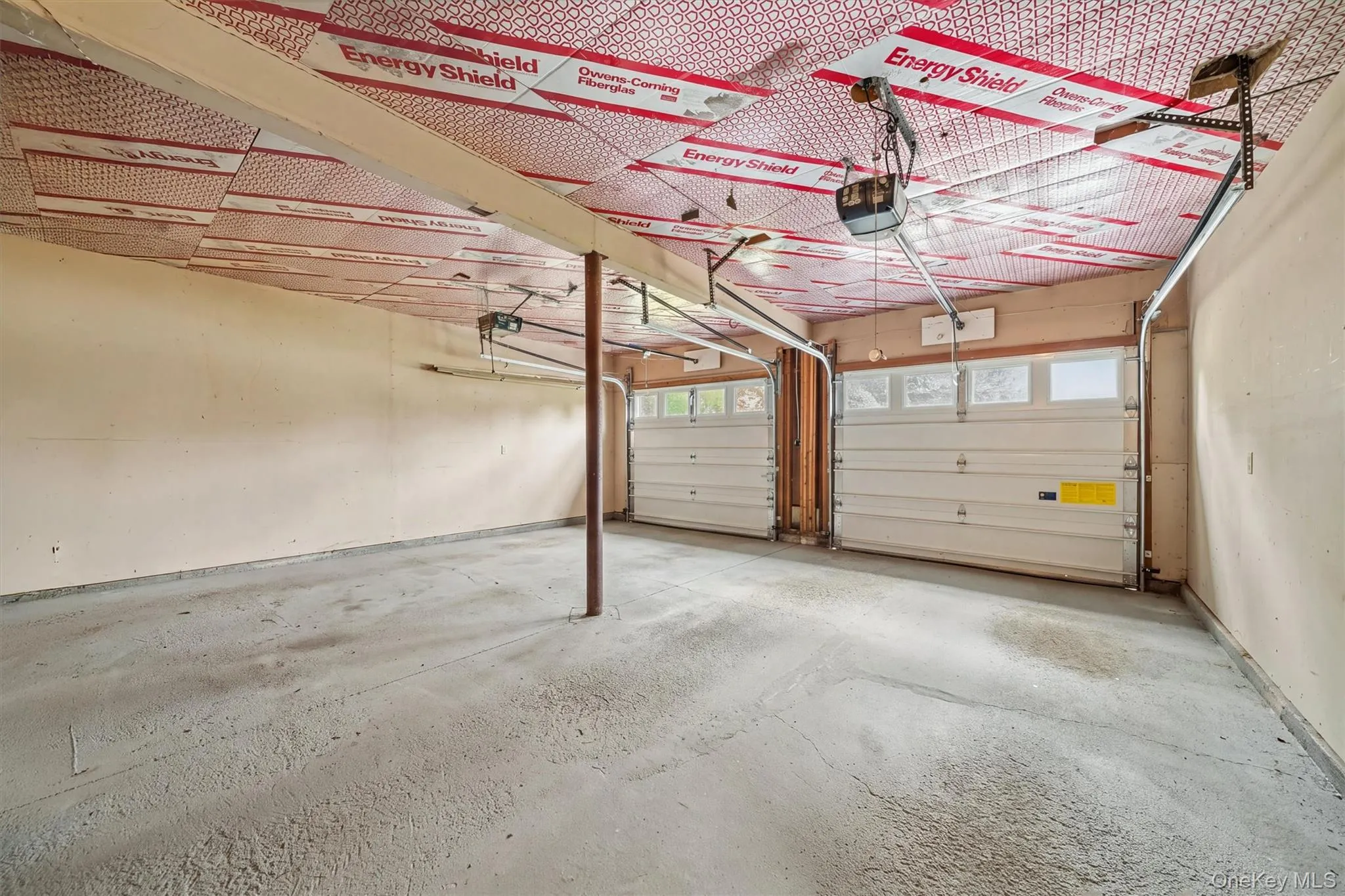 Two-car garage featuring a concrete floor, two garage doors with upper window panels, and an insulated ceiling Two-car garage featuring a concrete floor, two garage doors with upper window panels, and an insulated ceiling