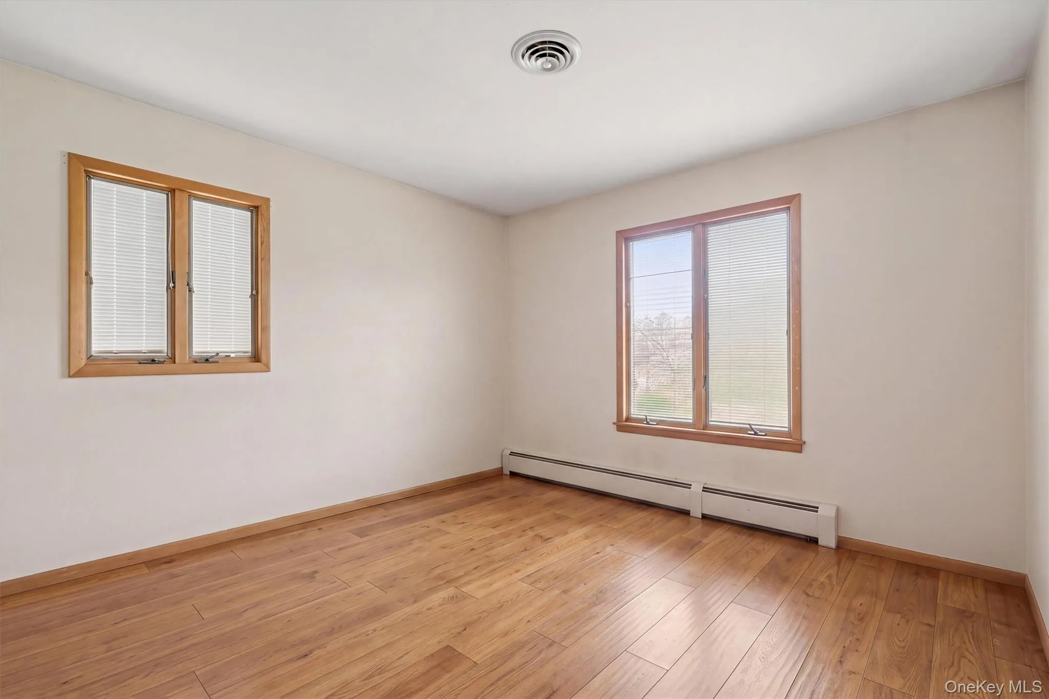 Bedroom 3 -- Wood-finish flooring with perimeter heating and multiple windows Bedroom 3 -- Wood-finish flooring with perimeter heating and multiple windows