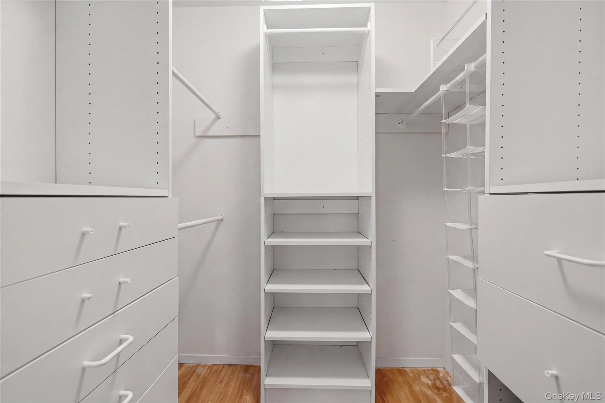 Primary Bedroom Custom built-in closet system featuring white shelving, integrated drawers with white pulls, and hanging rods Primary Bedroom Custom built-in closet system featuring white shelving, integrated drawers with white pulls, and hanging rods