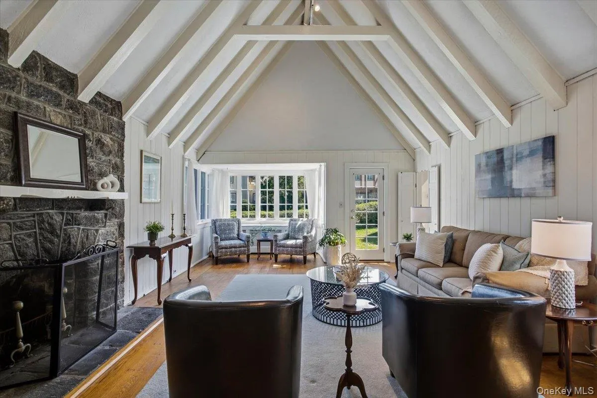 Dramatic living room with soaring cathedral ceilings, abundant natural light, and a wood-burning fireplace Dramatic living room with soaring cathedral ceilings, abundant natural light, and a wood-burning fireplace