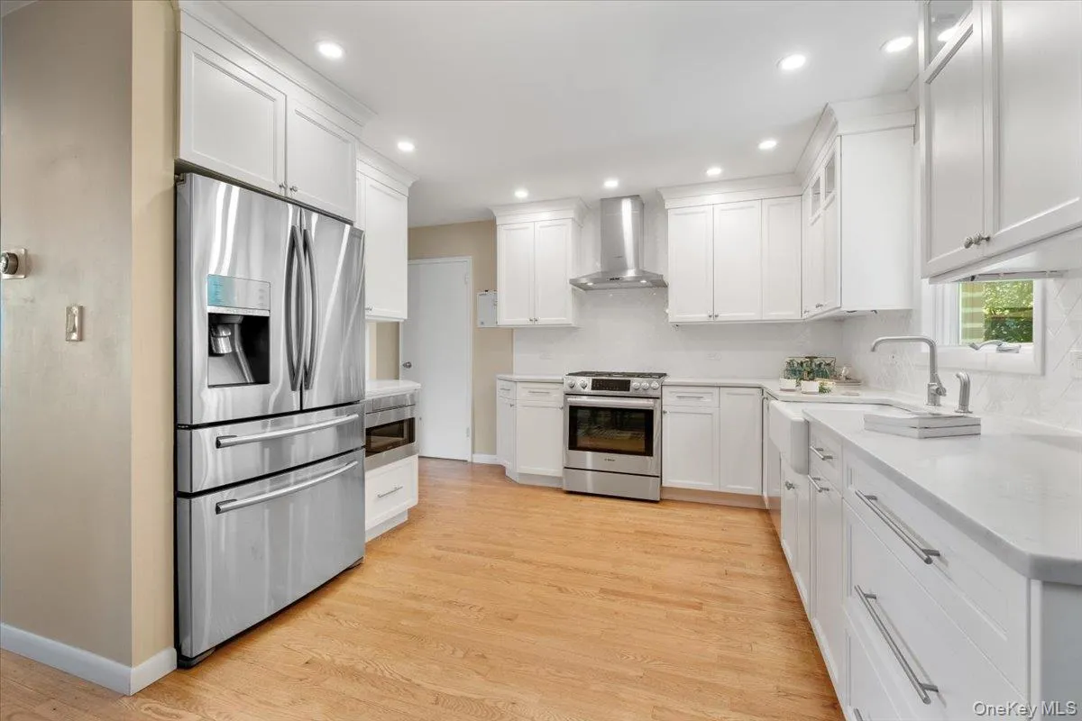 Renovated kitchen features white cabinetry, stainless steel appliances, hardwood flooring Renovated kitchen features white cabinetry, stainless steel appliances, hardwood flooring