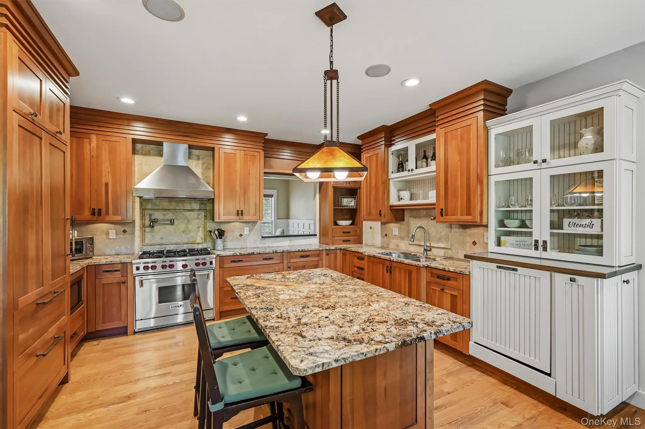 The well-appointed kitchen is anchored by a stunning Wolf gas range and complemented by premium appliances, granite countertops, cherry cabinetry, and a generous center island. The well-appointed kitchen is anchored by a stunning Wolf gas range and complemented by premium appliances, granite countertops, cherry cabinetry, and a generous center island.