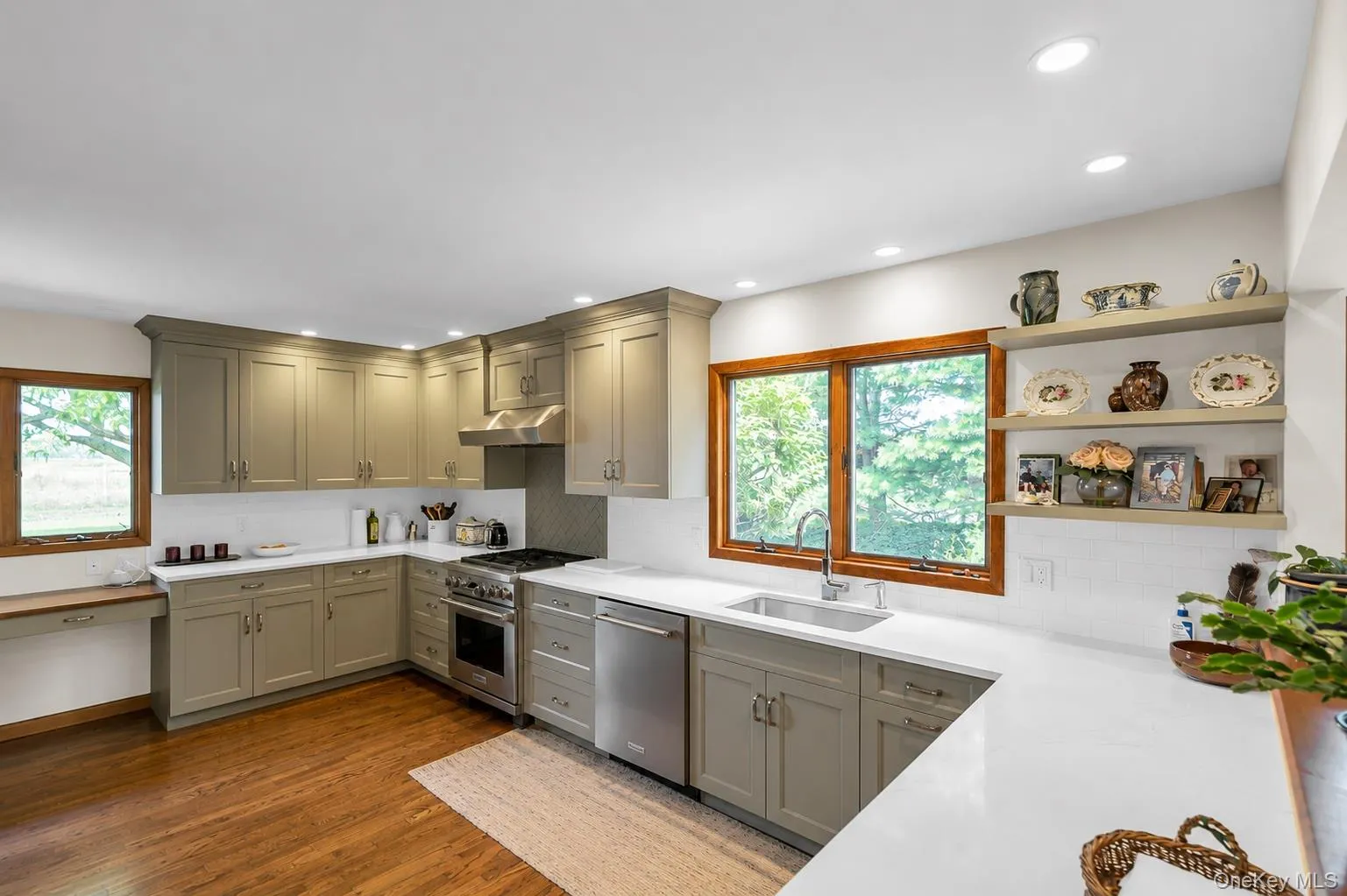 Kitchen featuring extensive cabinetry, stainless steel appliances, quartz countertops, and wood-finish flooring Kitchen featuring extensive cabinetry, stainless steel appliances, quartz countertops, and wood-finish flooring