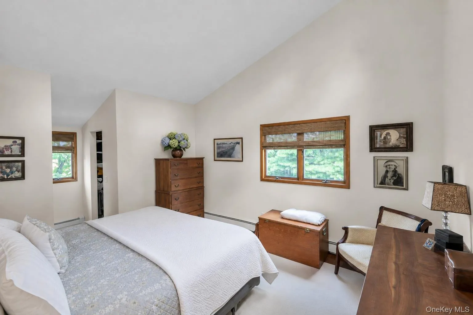 Vaulted ceiling primary bedroom with natural light through wood-framed windows. Fits a king size bed Vaulted ceiling primary bedroom with natural light through wood-framed windows. Fits a king size bed