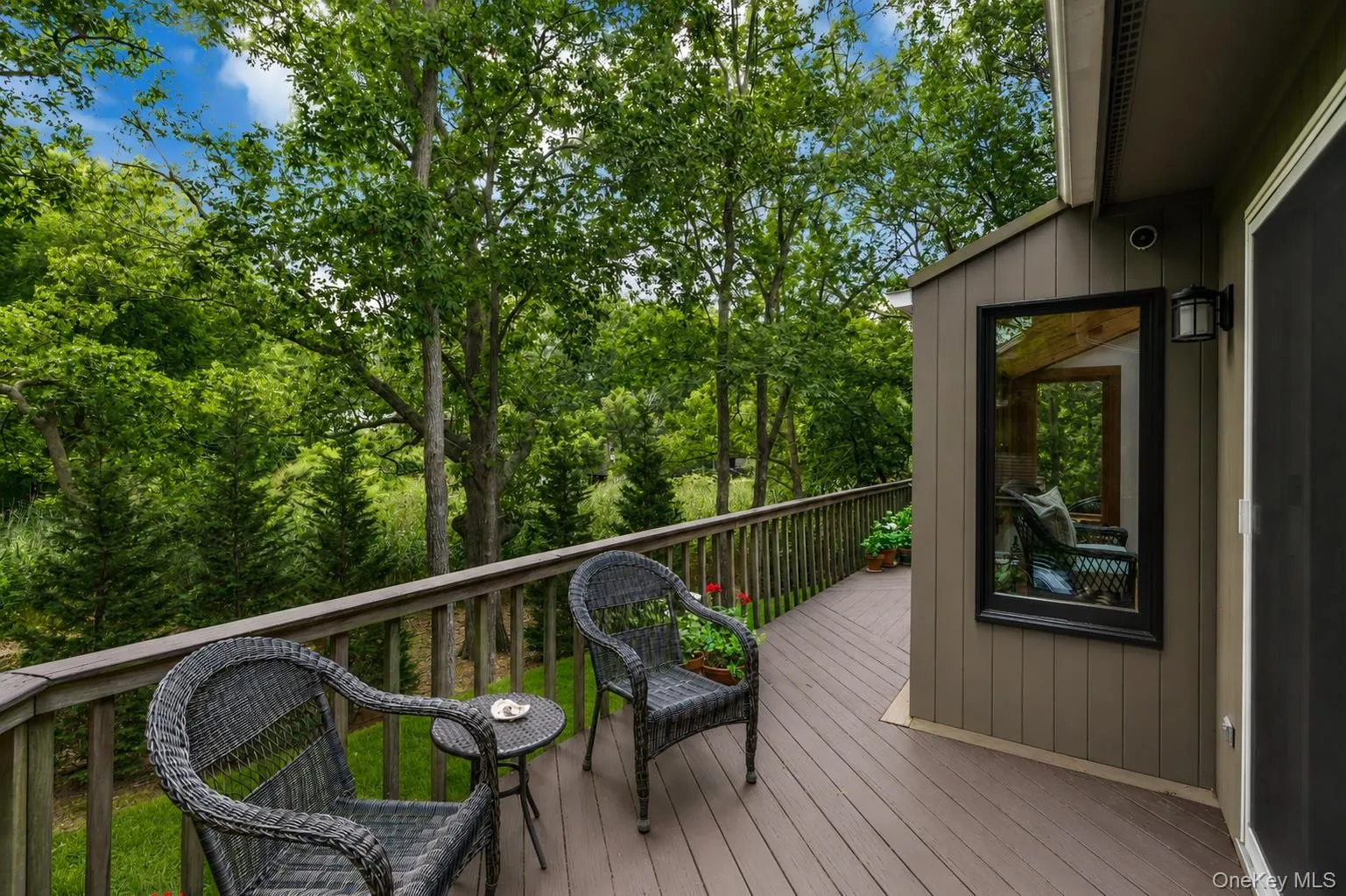 Spacious outdoor deck with wood-finish flooring, wood railing, and surrounding mature trees Spacious outdoor deck with wood-finish flooring, wood railing, and surrounding mature trees