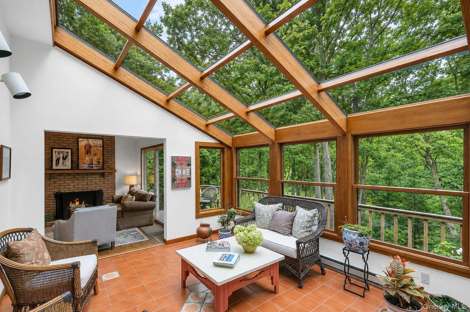 Sunroom with a full glass roof, natural wood beam construction, terracotta tile flooring, and a brick fireplace Sunroom with a full glass roof, natural wood beam construction, terracotta tile flooring, and a brick fireplace